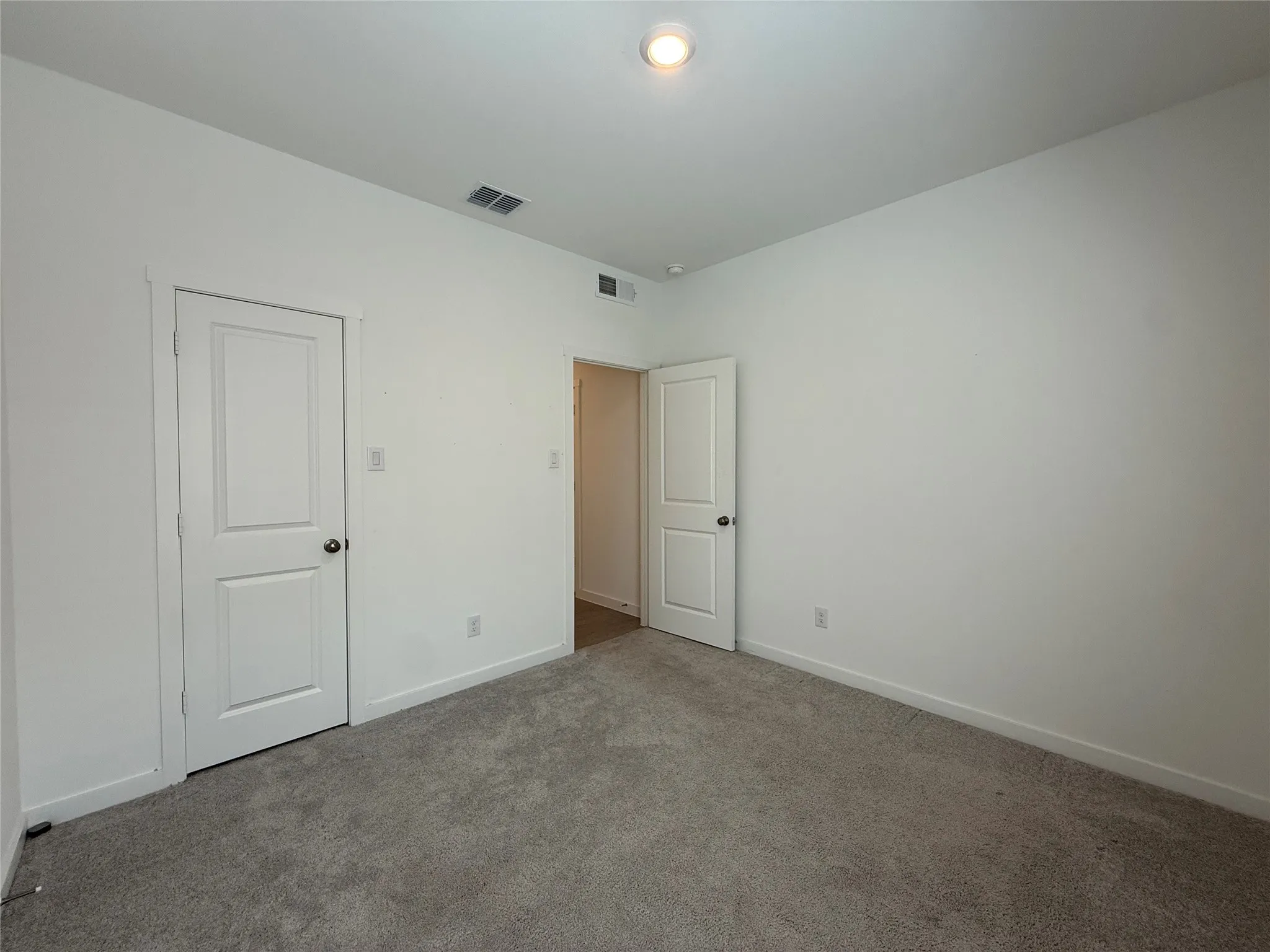 Neutral wall finishes, recessed ceiling lighting, and gray carpet flooring
