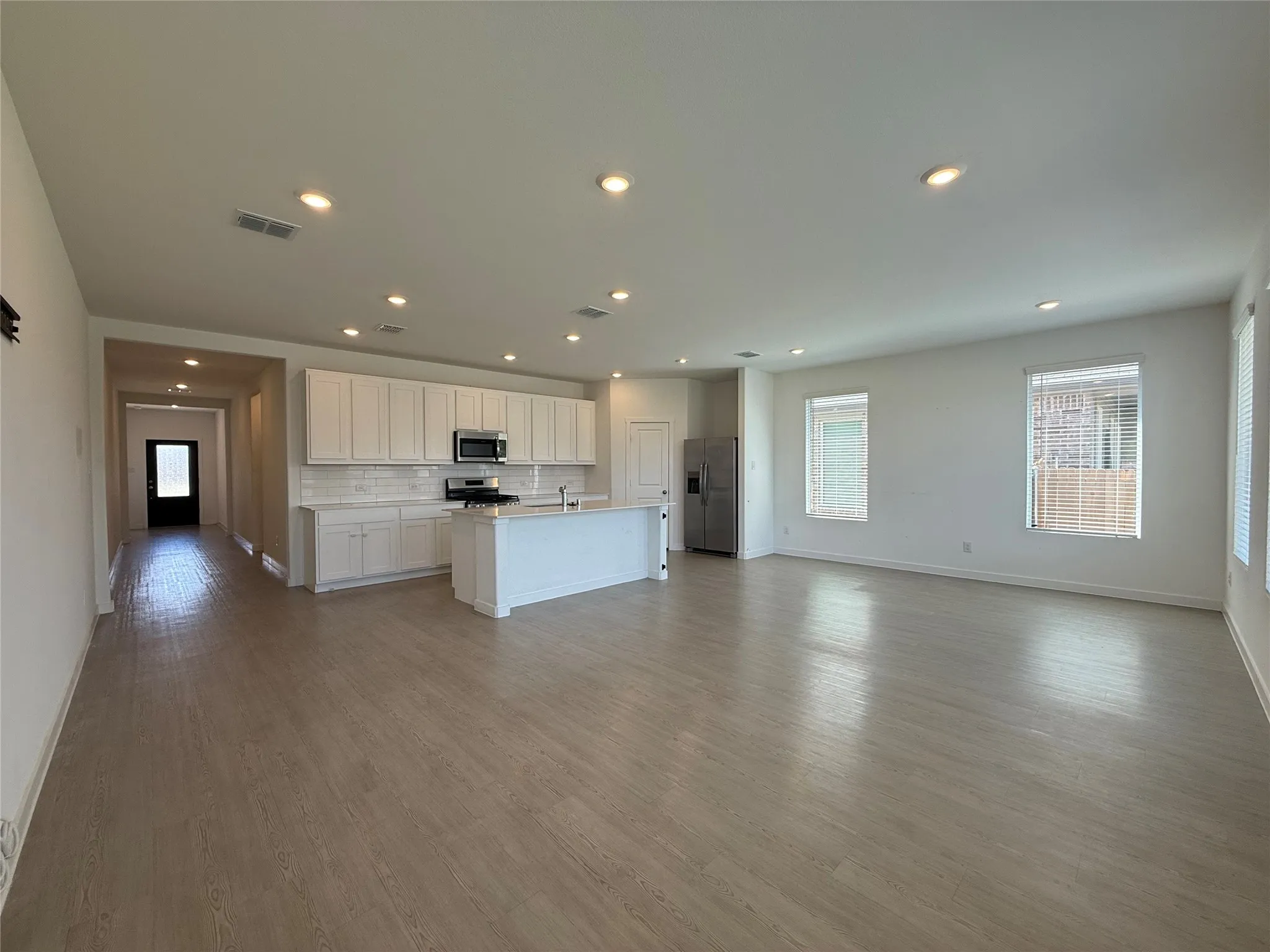 Open-concept living space featuring wood-finish flooring, recessed lighting, and multiple windows