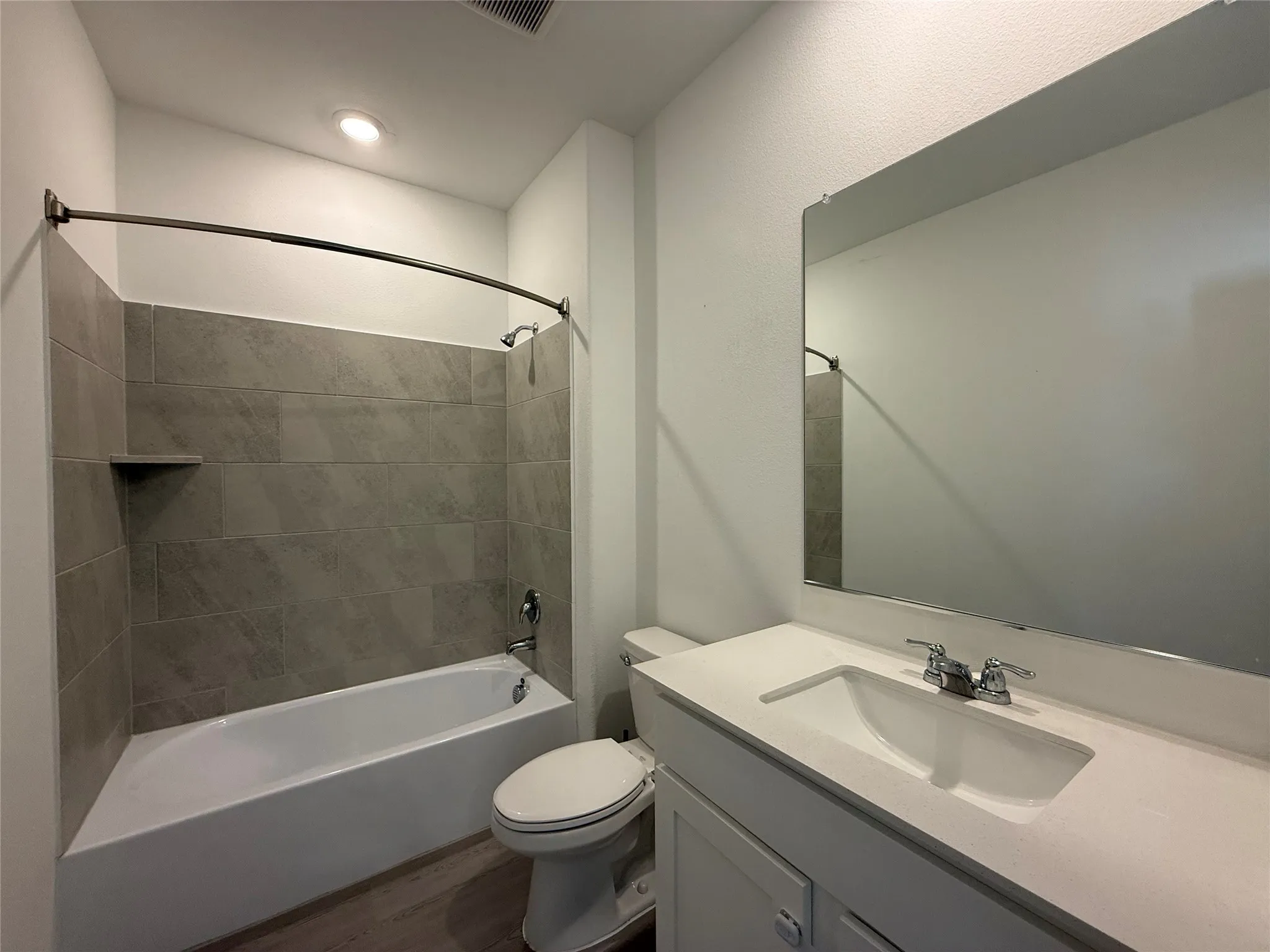 Bathroom featuring a white vanity with integrated sink, chrome faucet, and expansive wall-mounted mirror