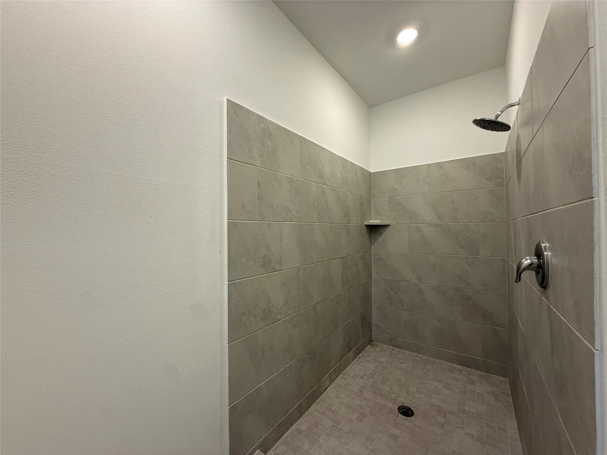 Tiled shower with a built-in corner shelf and a rain showerhead
