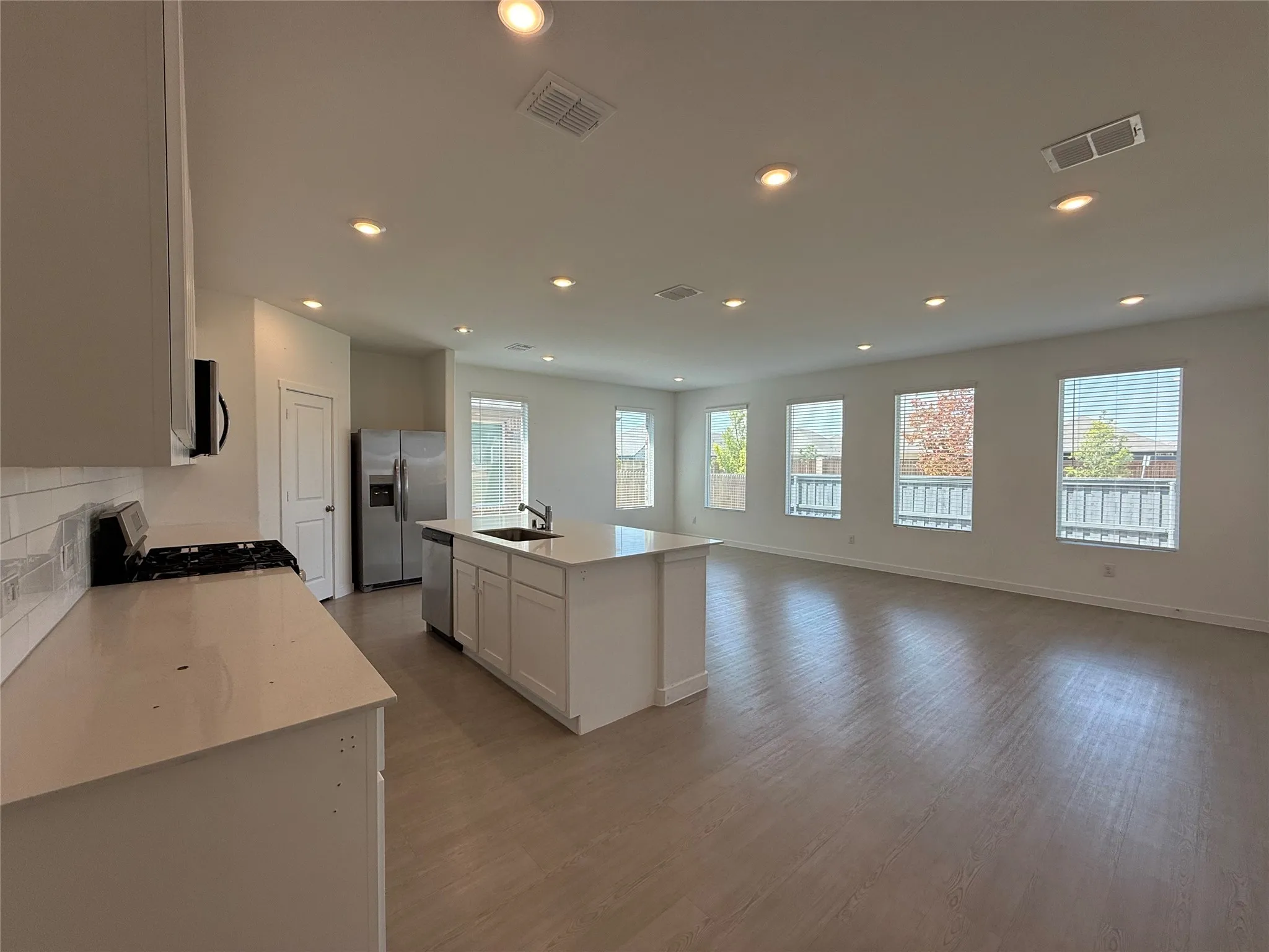 Open-concept living area with wood-finish flooring, recessed lighting, and multiple​​‌​​​​‌​​‌‌​‌‌​​​‌‌​‌​‌​‌​​​‌​​ windows