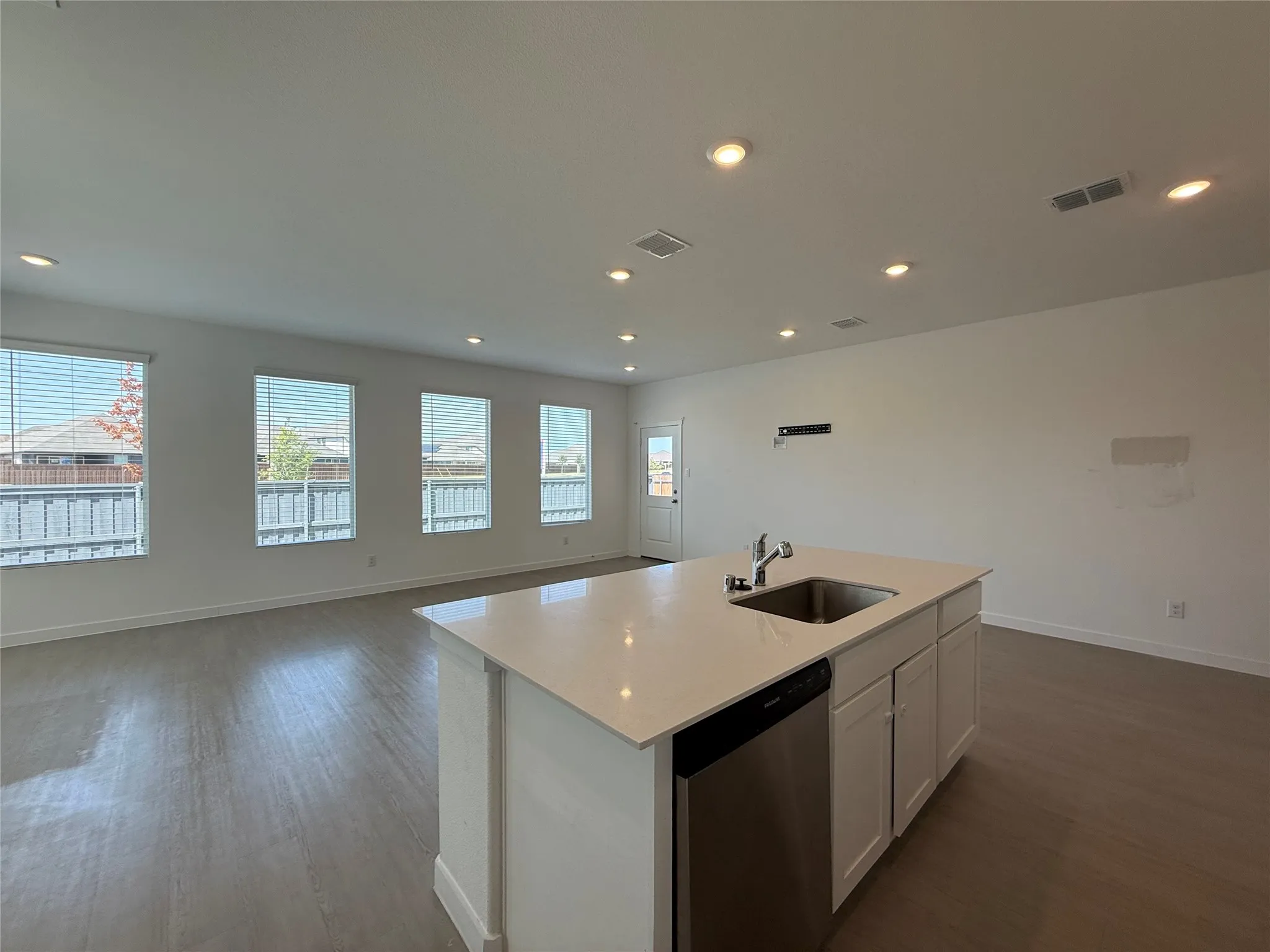 Kitchen island with an undermount sink, stainless steel dishwasher, and light-toned countertop