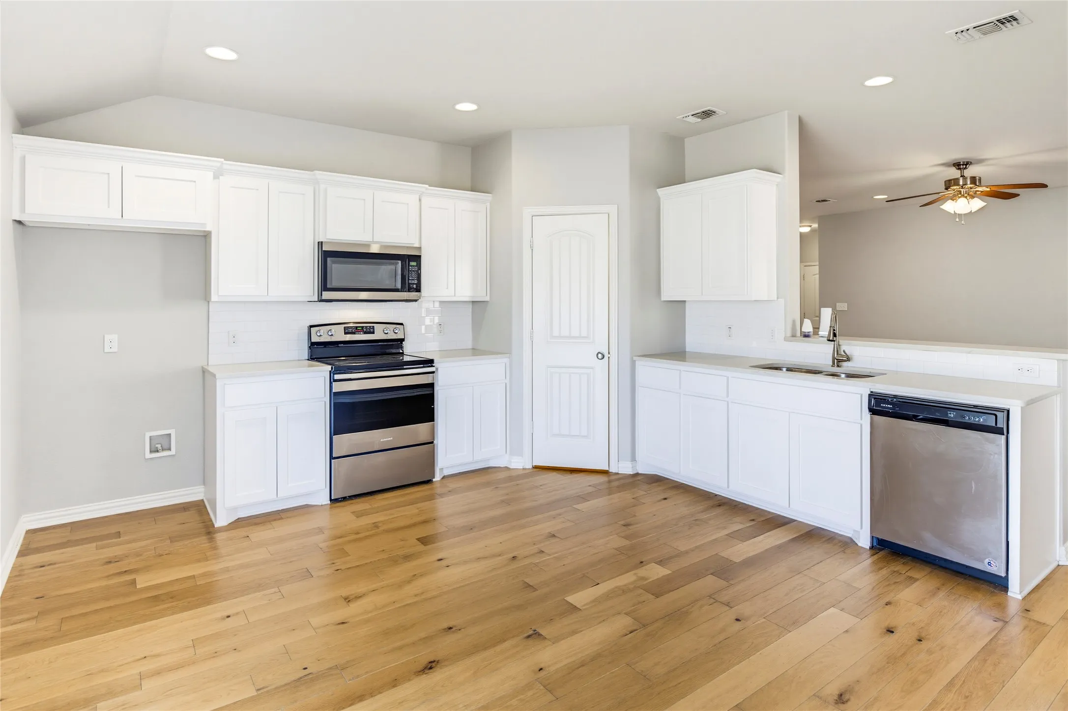 Kitchen featuring white cabinetry, stainless steel appliances, light-toned wood-finish flooring, and recessed lighting