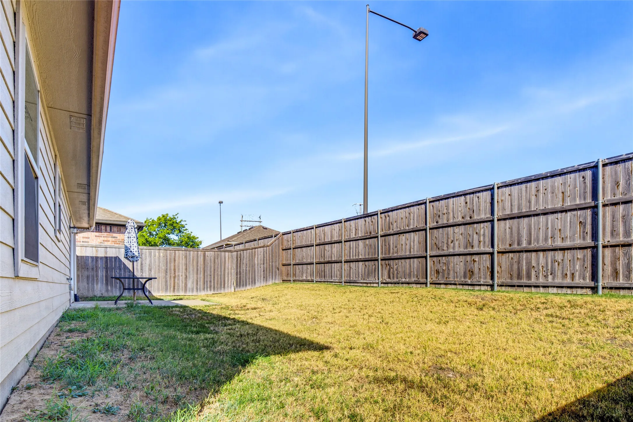 Expansive backyard featuring a wood fence, concrete patio, and exterior siding