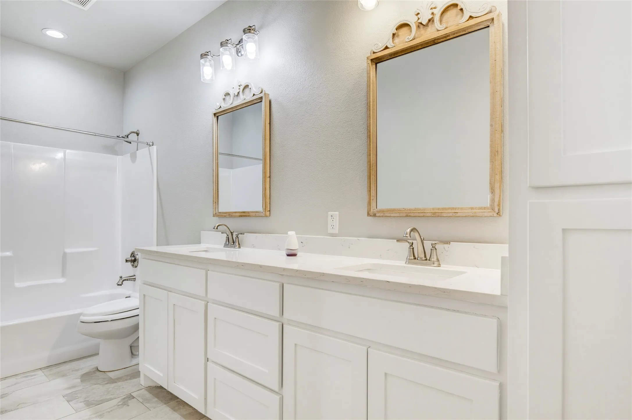 Dual vanity with white cabinetry, light-toned countertops, and brushed nickel fixtures