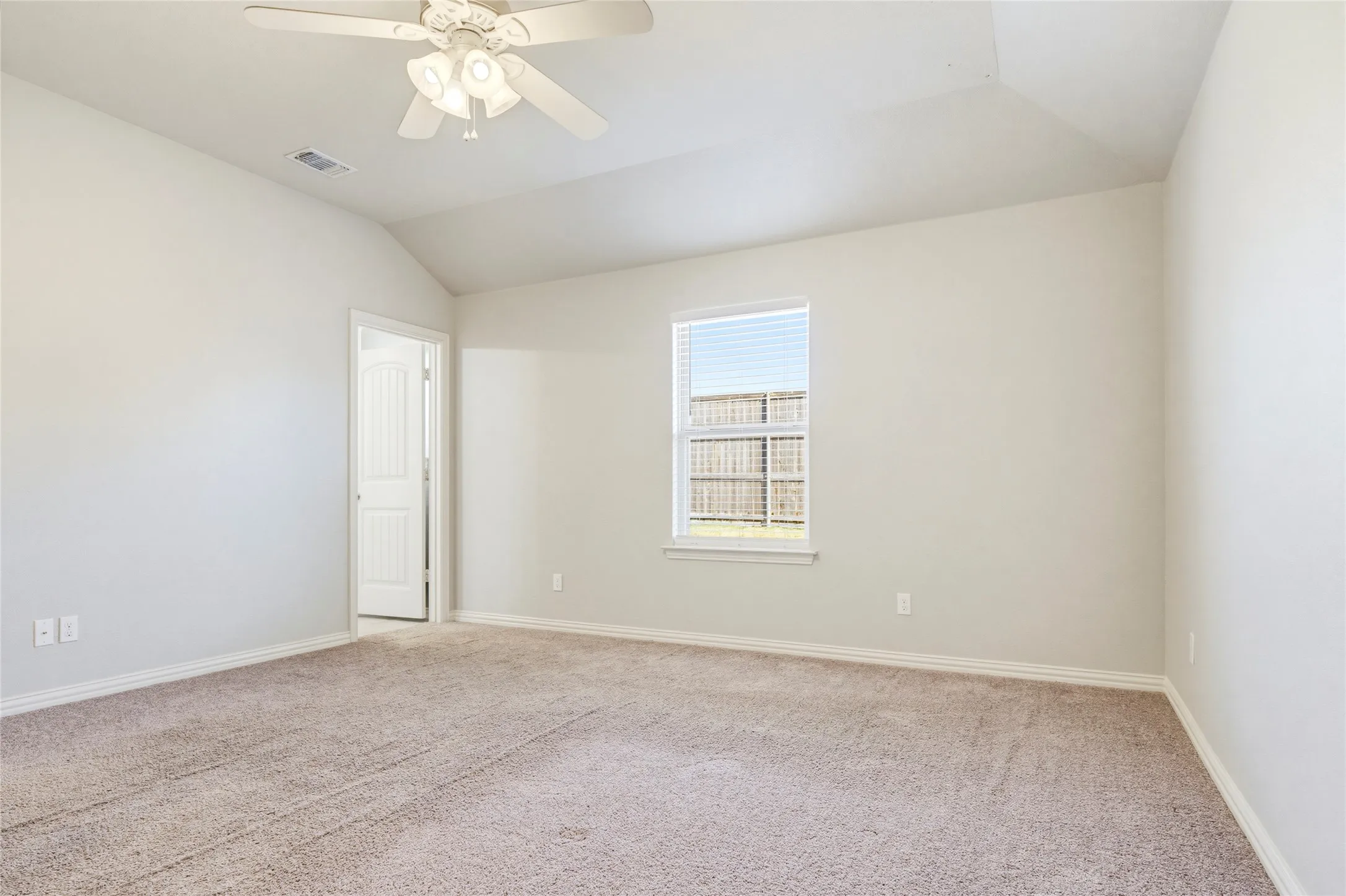 Carpeted room with a vaulted ceiling, ceiling fan, and a window with blinds