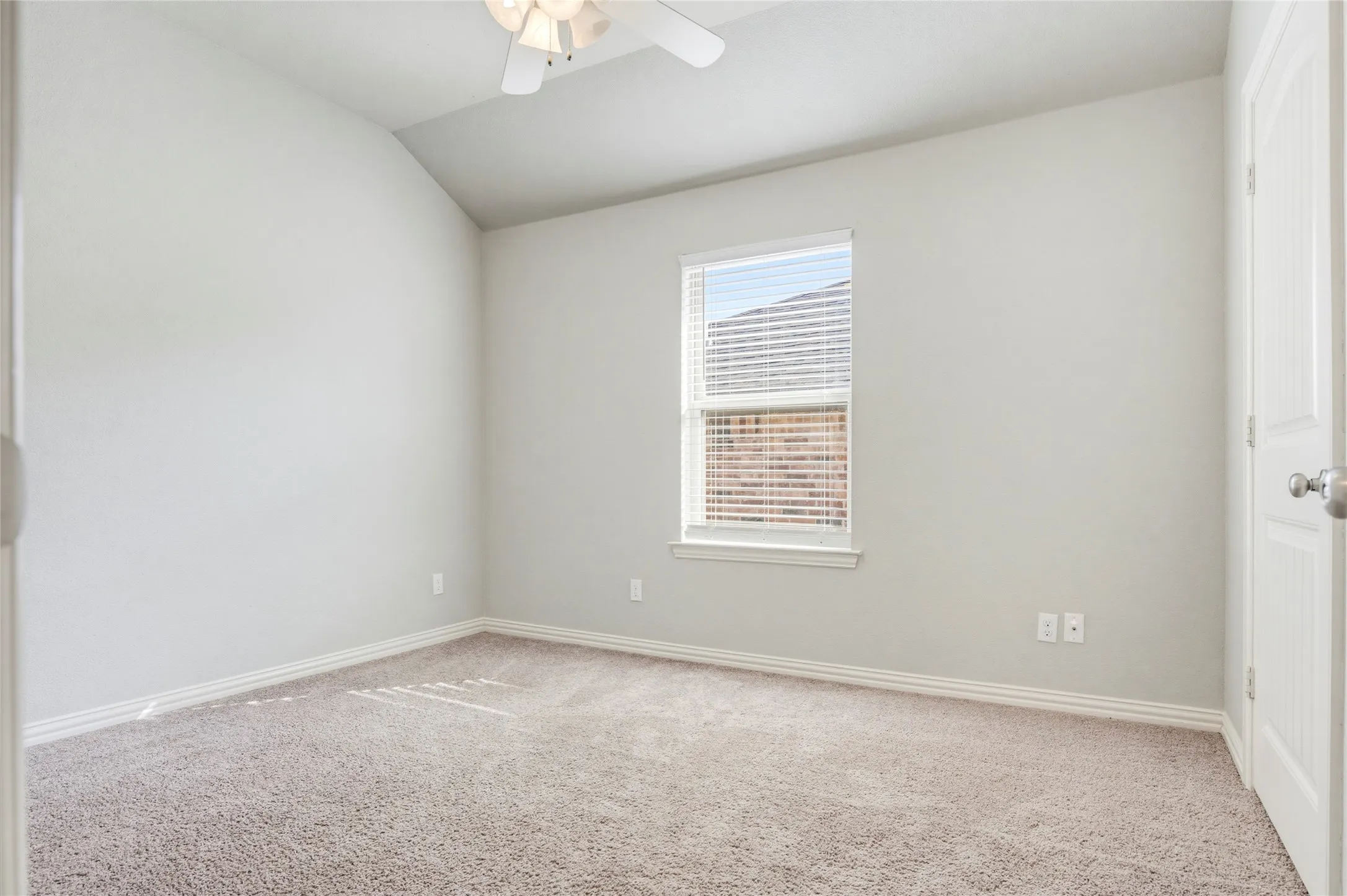 Carpeted room with a vaulted ceiling, ceiling fan, and a window with blinds