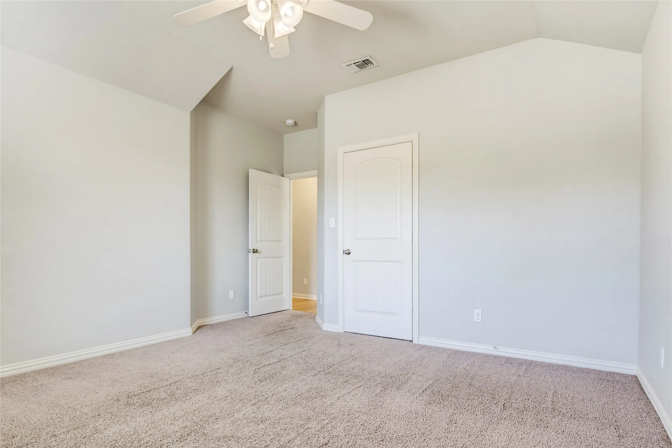 Vaulted ceiling, ceiling fan, neutral wall paint, white trim, and carpeted flooring