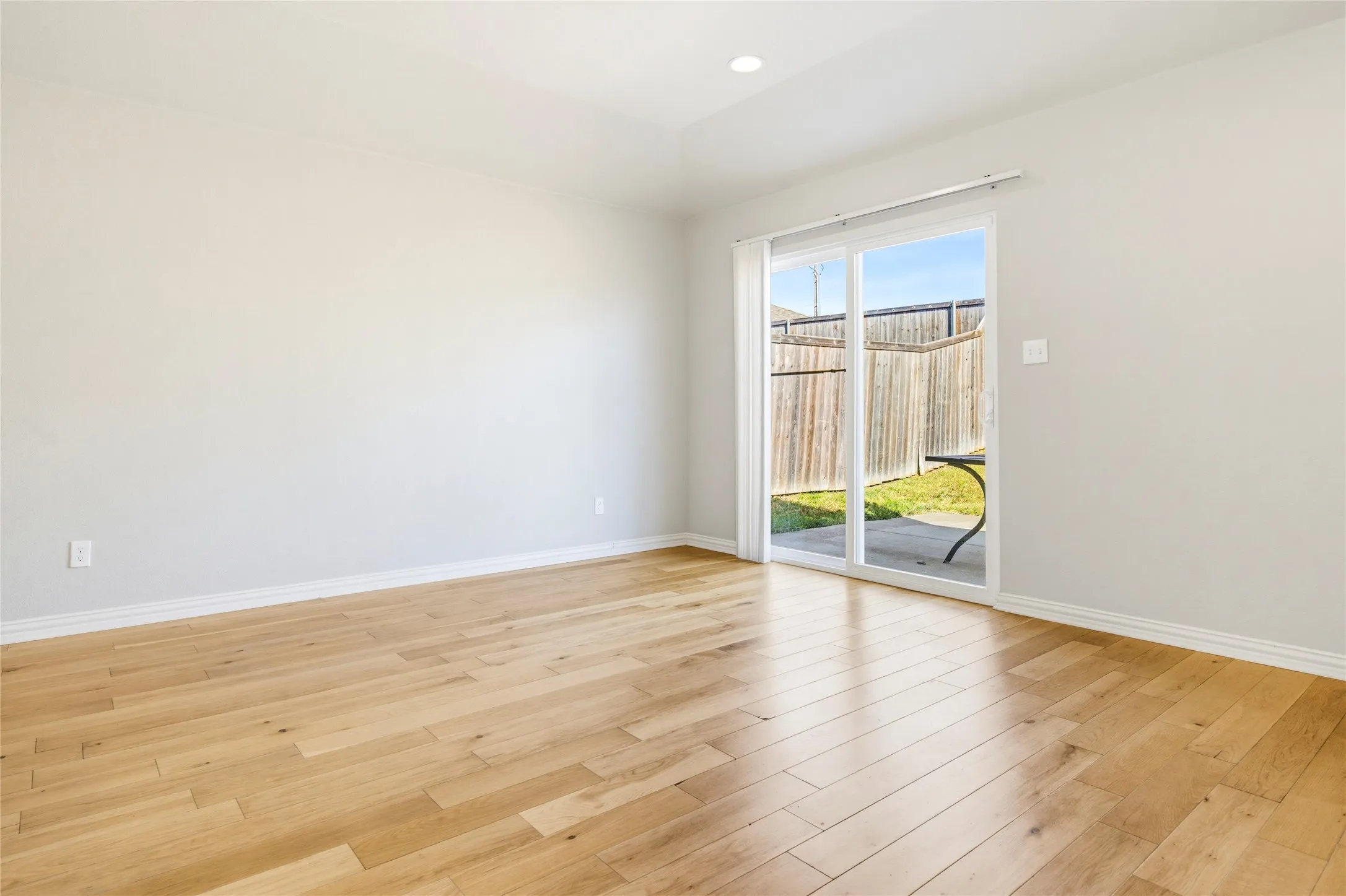 Hardwood flooring, light-toned walls, recessed lighting, and sliding glass door to outdoor patio