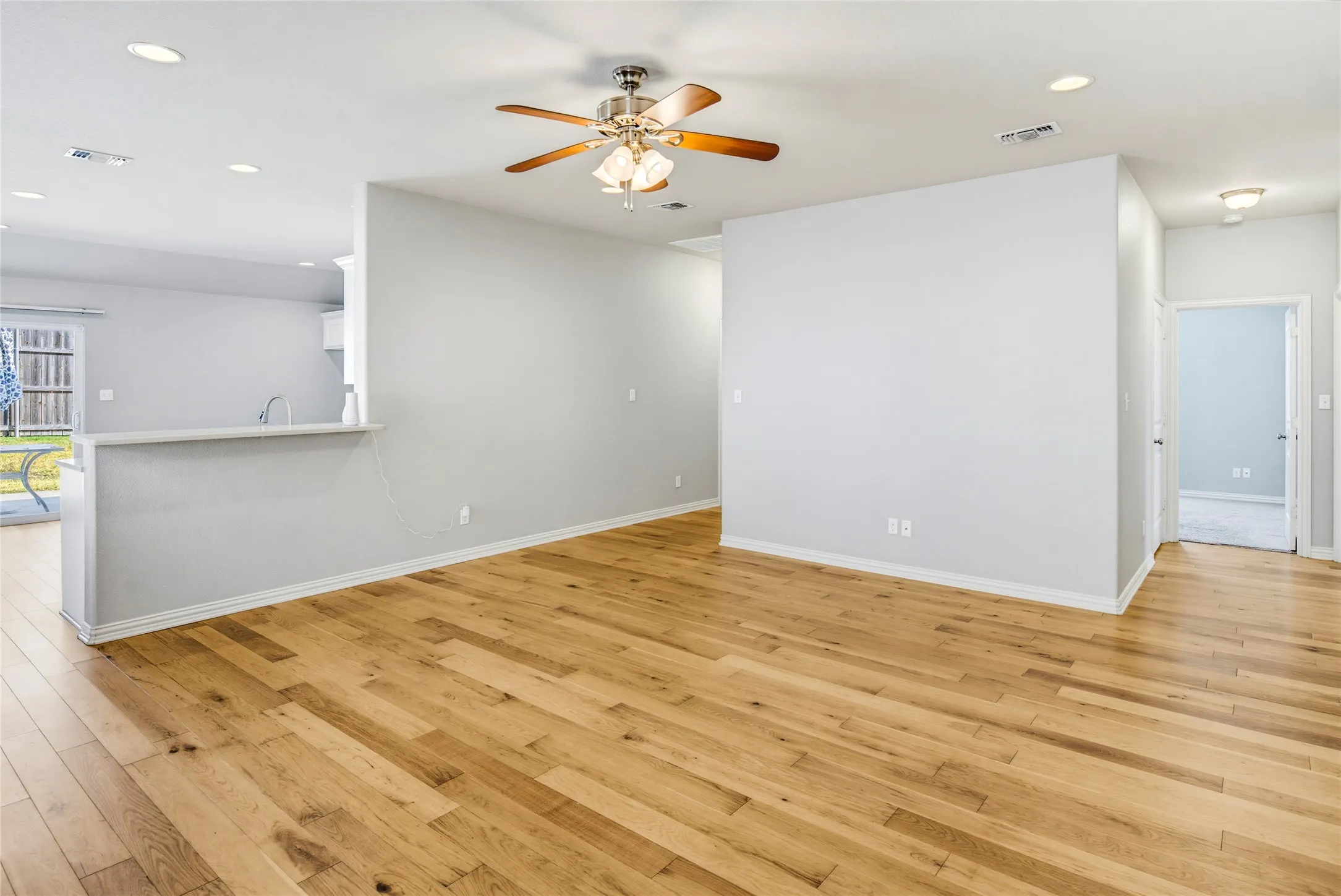 Wood-finish flooring throughout, recessed lighting, and a ceiling fan with integrated light