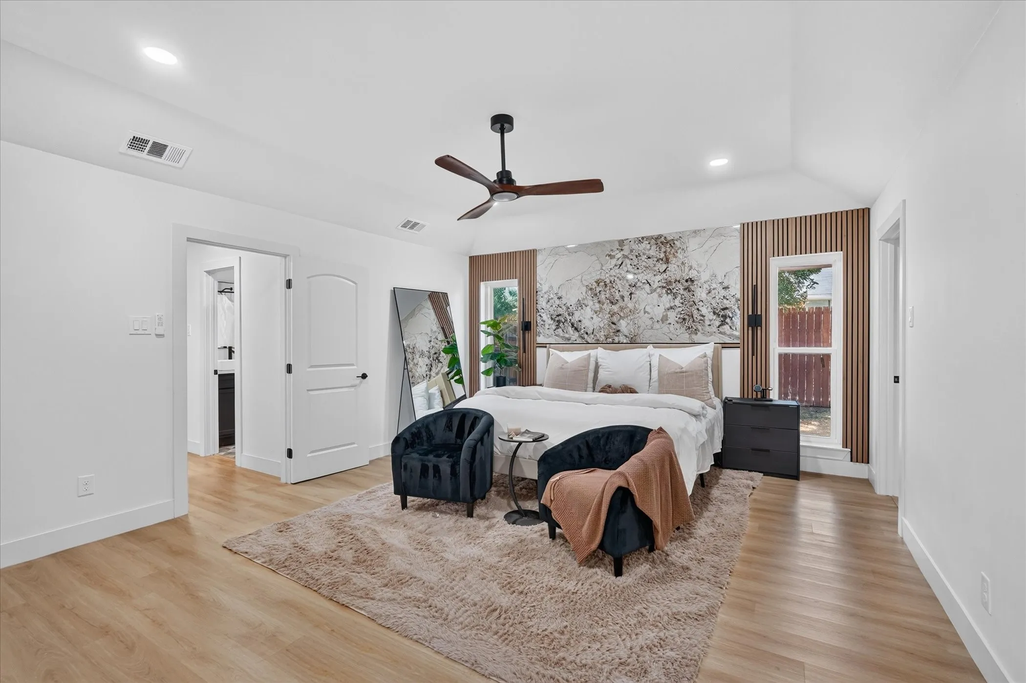 Vaulted ceiling with a ceiling fan, light wood-finish flooring, recessed lighting, and a decorative wall panel accent