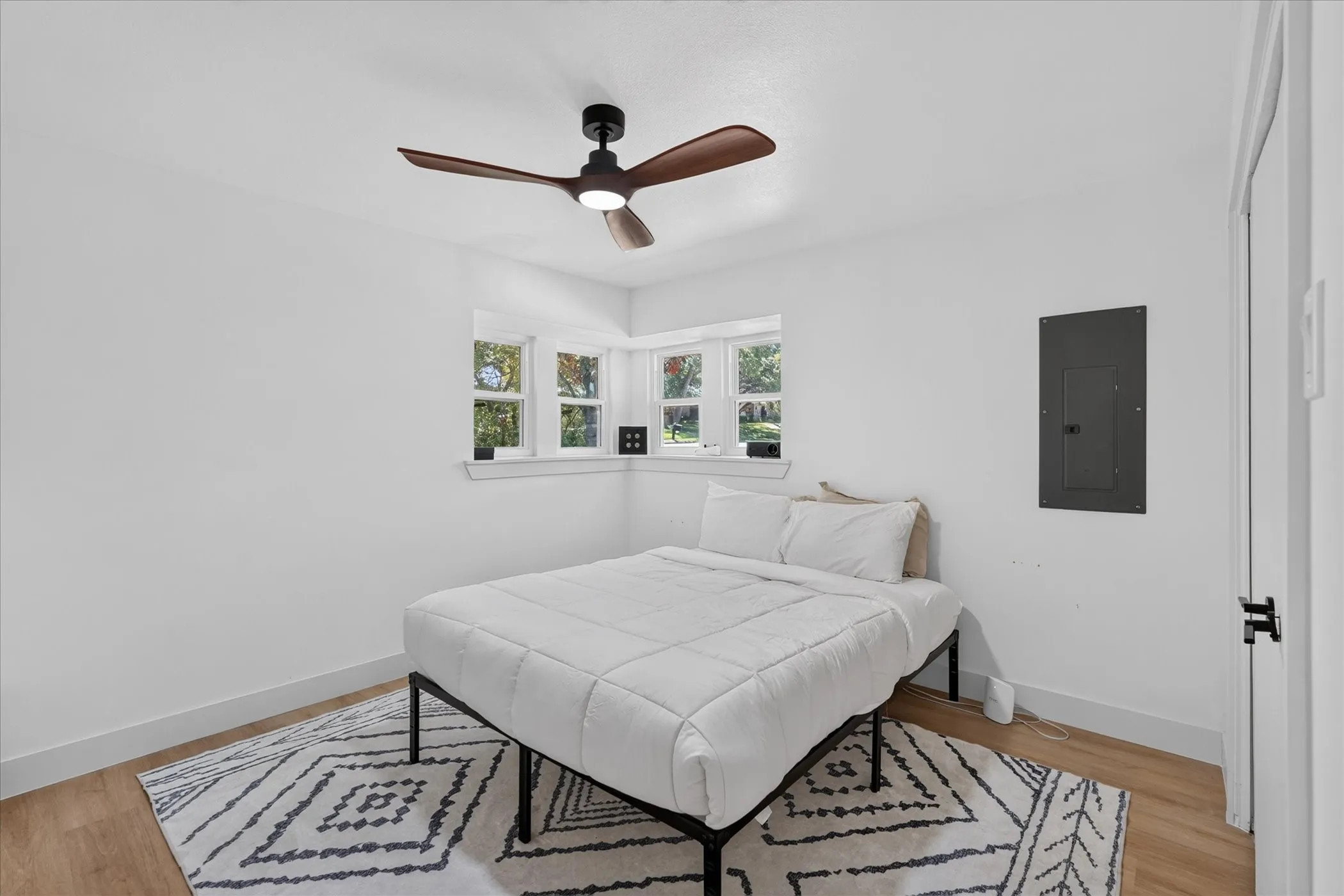 Recessed bay window, modern ceiling fan, wood-finish flooring, white walls, and white trim