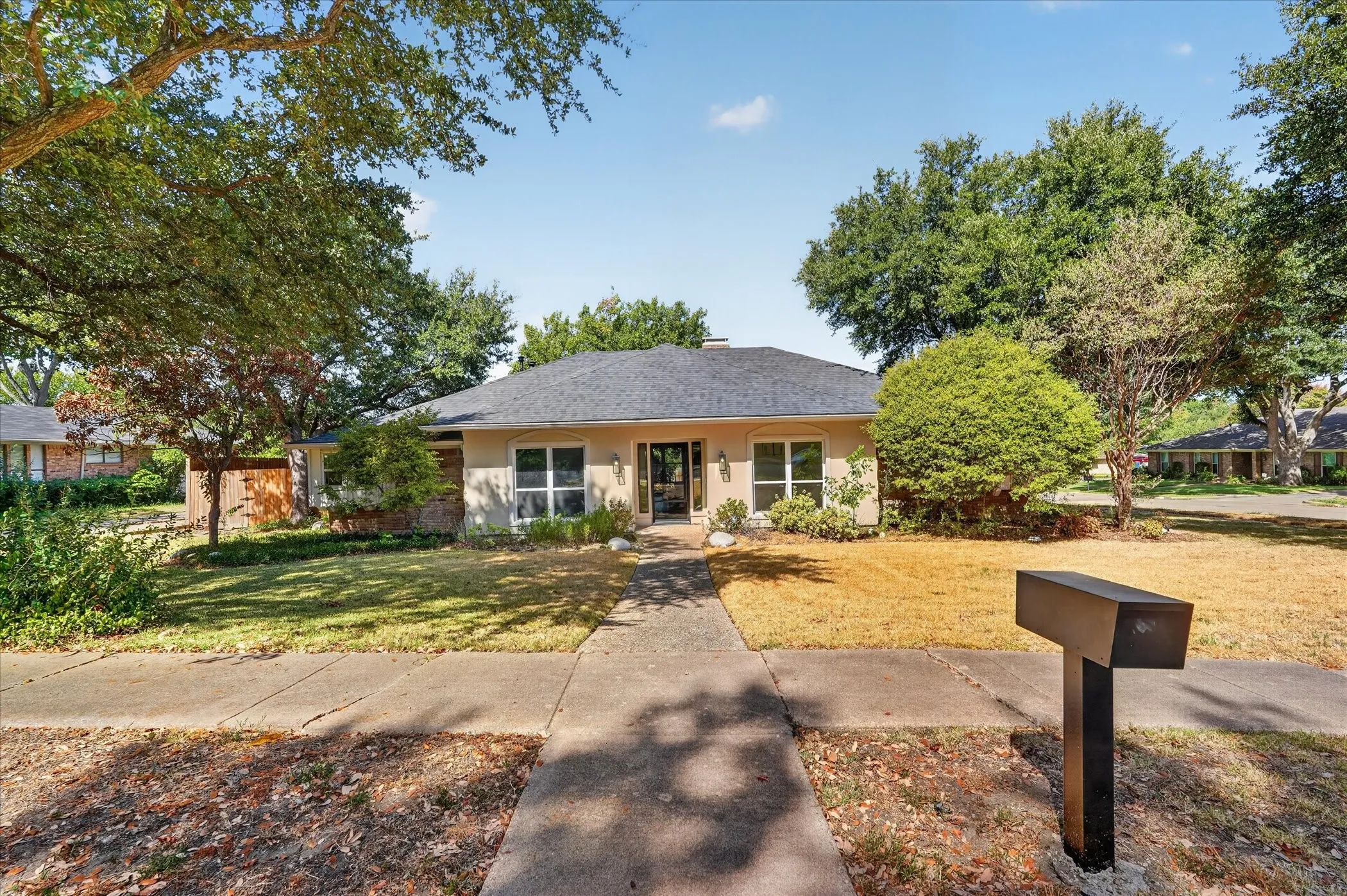 Ranch-style exterior with a dark shingle roof, stucco siding, and multiple front windows