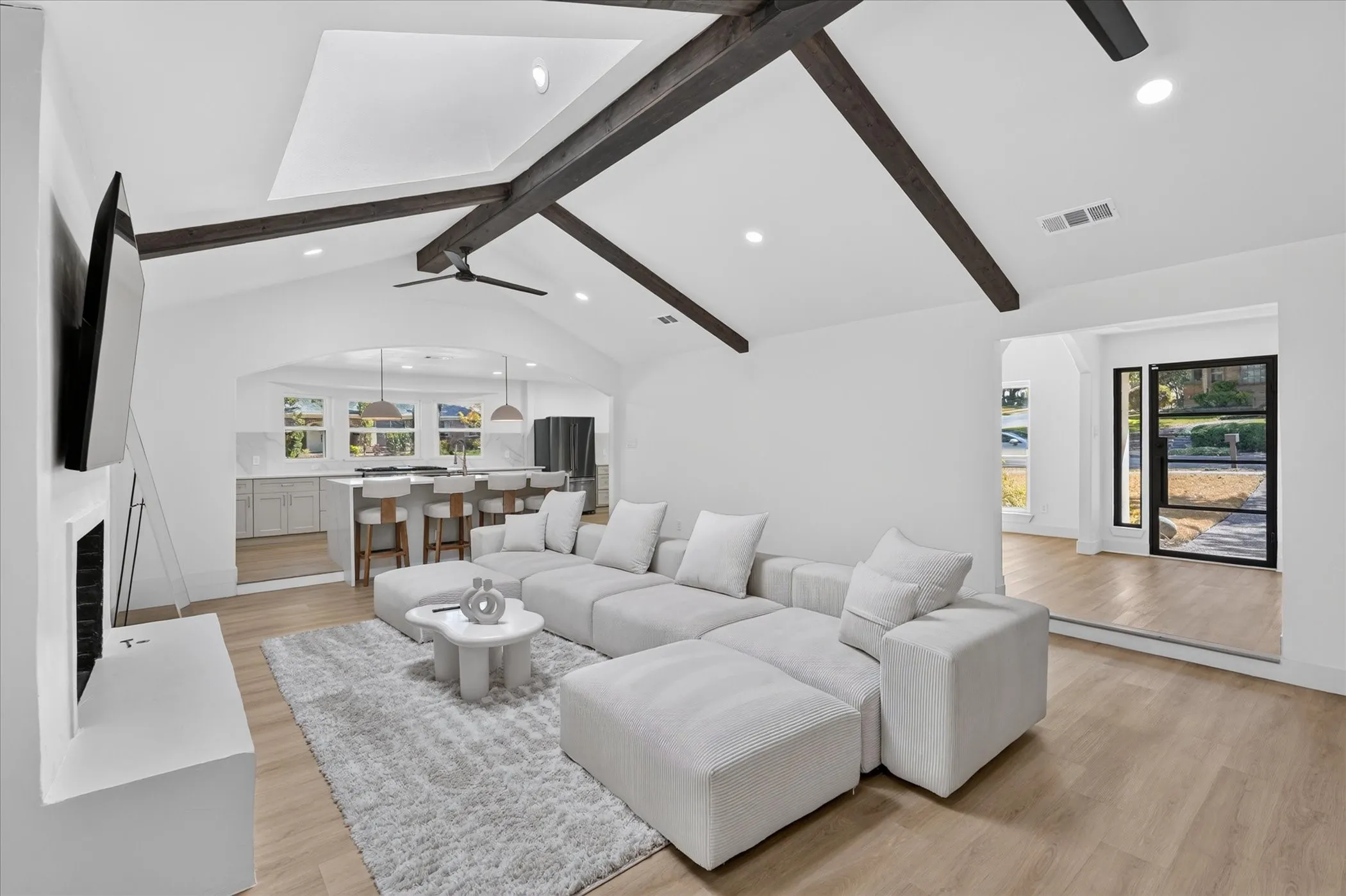 Vaulted ceilings with exposed wood beams, recessed lighting, and wood-finish flooring