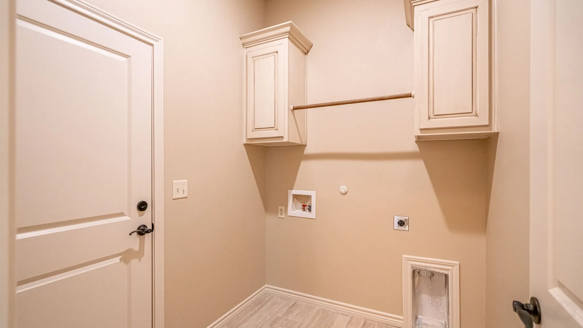 Full sized laundry room with washer and dryer hook ups, cabinets and drying rod