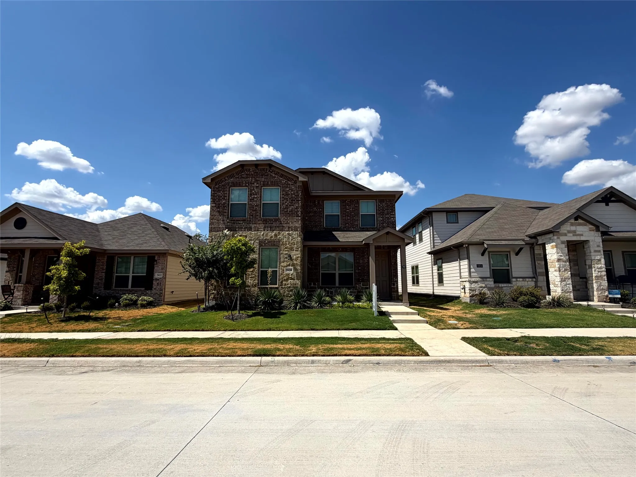 Two-story residence featuring a brick and stone facade, covered entry porch, and an attached two-car garage