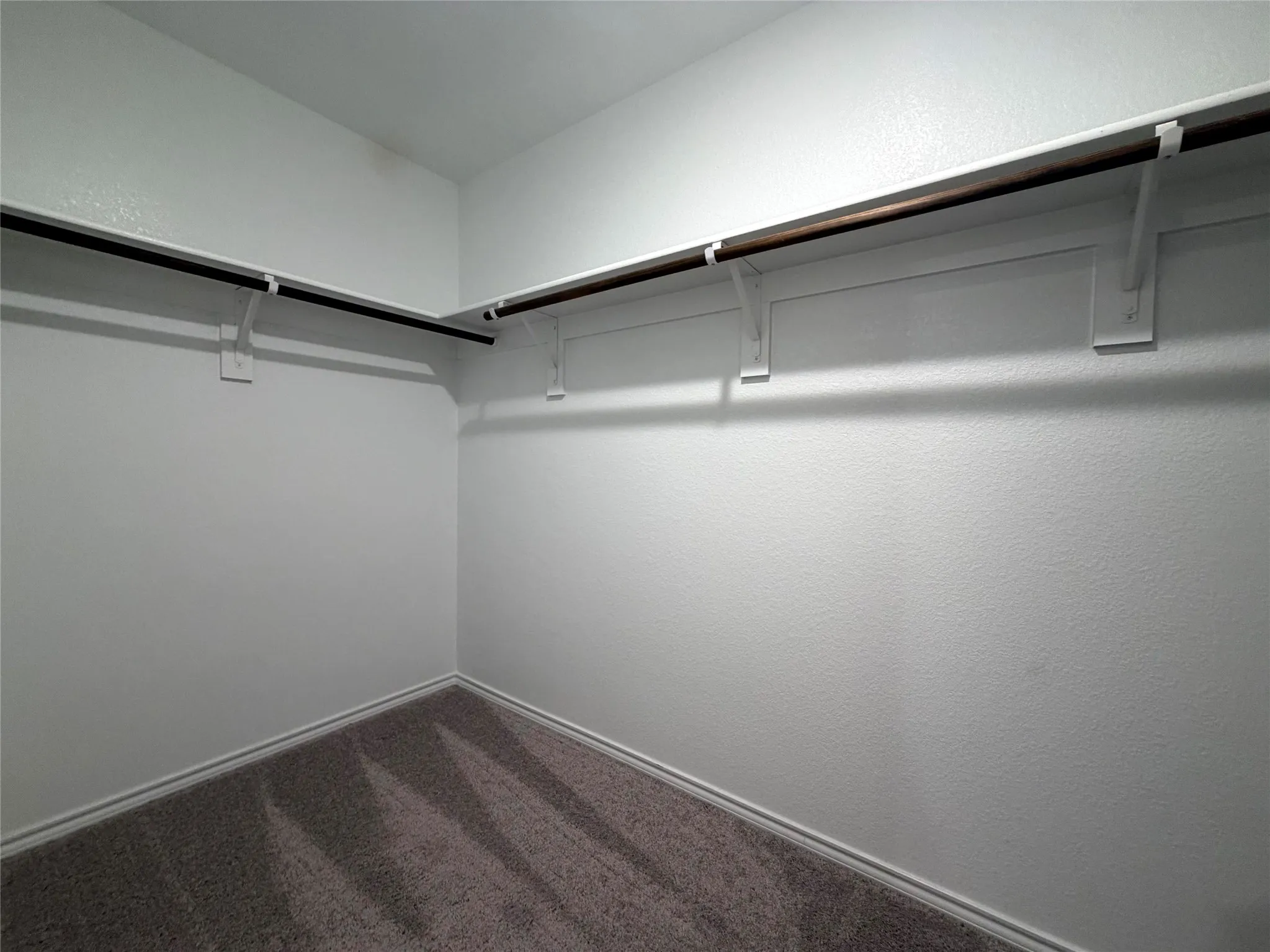 Corner closet with grey carpet flooring and white walls