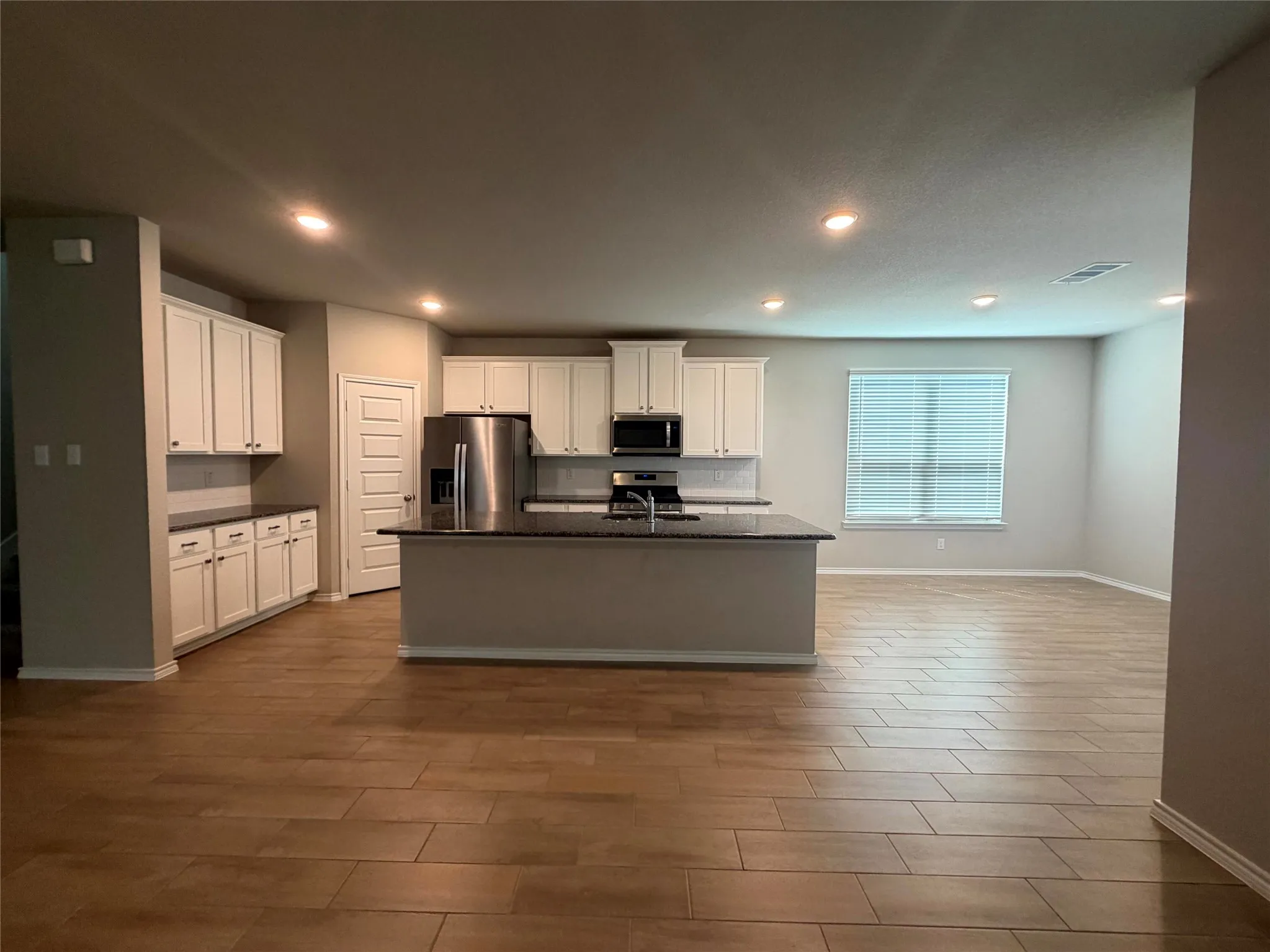 Kitchen featuring white cabinetry, dark countertops, stainless steel appliances, and wood-finish flooring