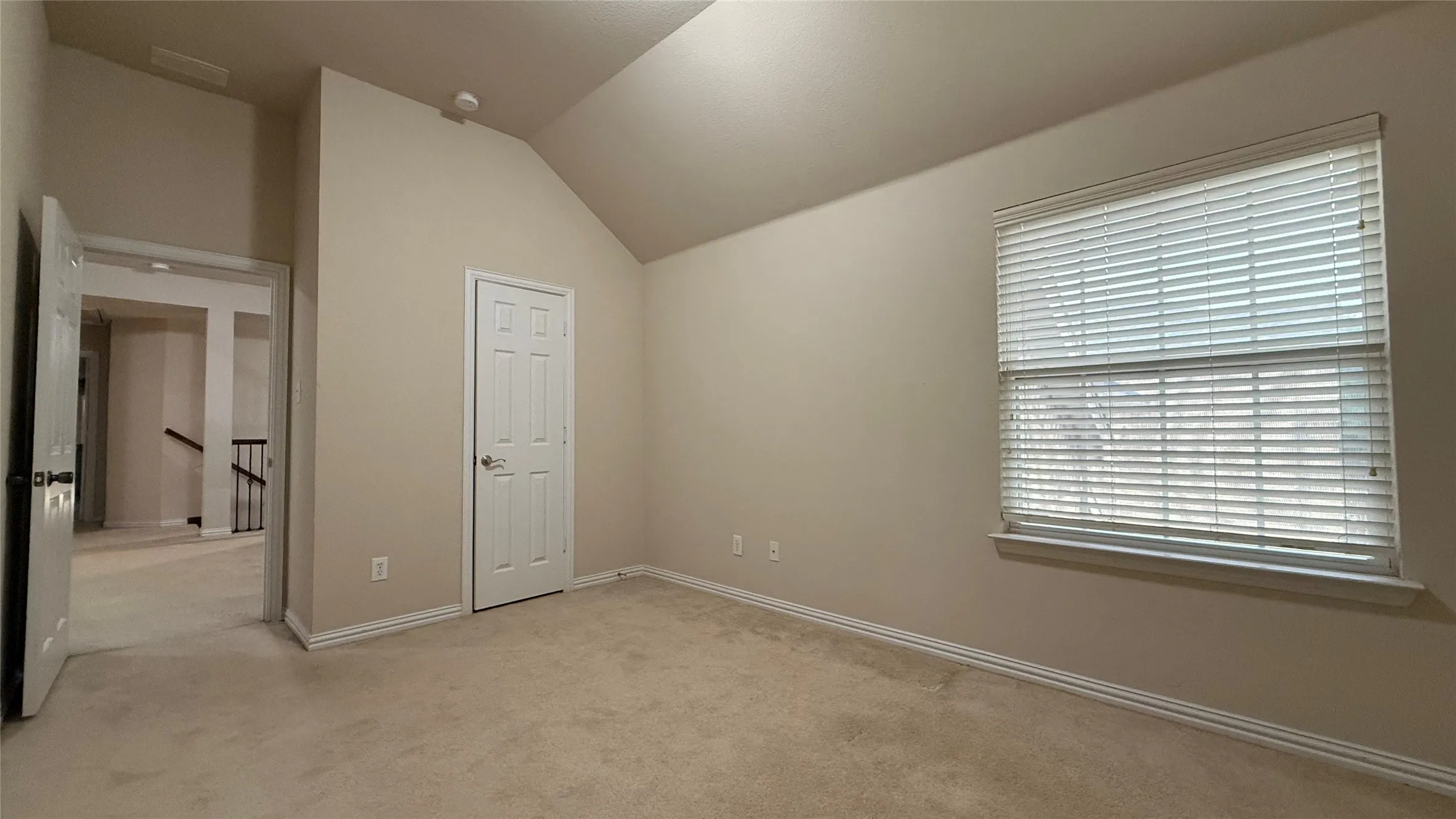 Vaulted ceiling, carpeted flooring, window with blinds, panel door, neutral wall paint