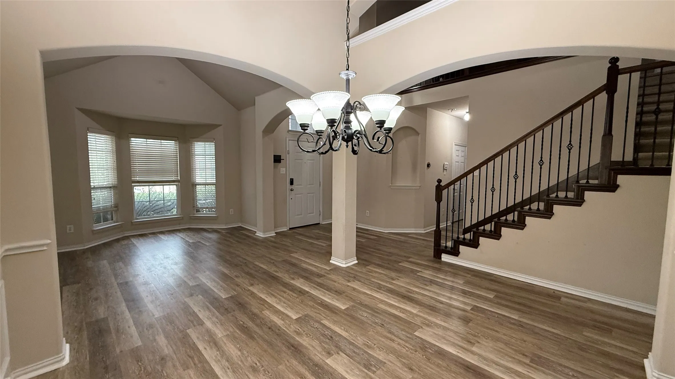 Wood-finish flooring throughout, complemented by arched doorways and a bay window