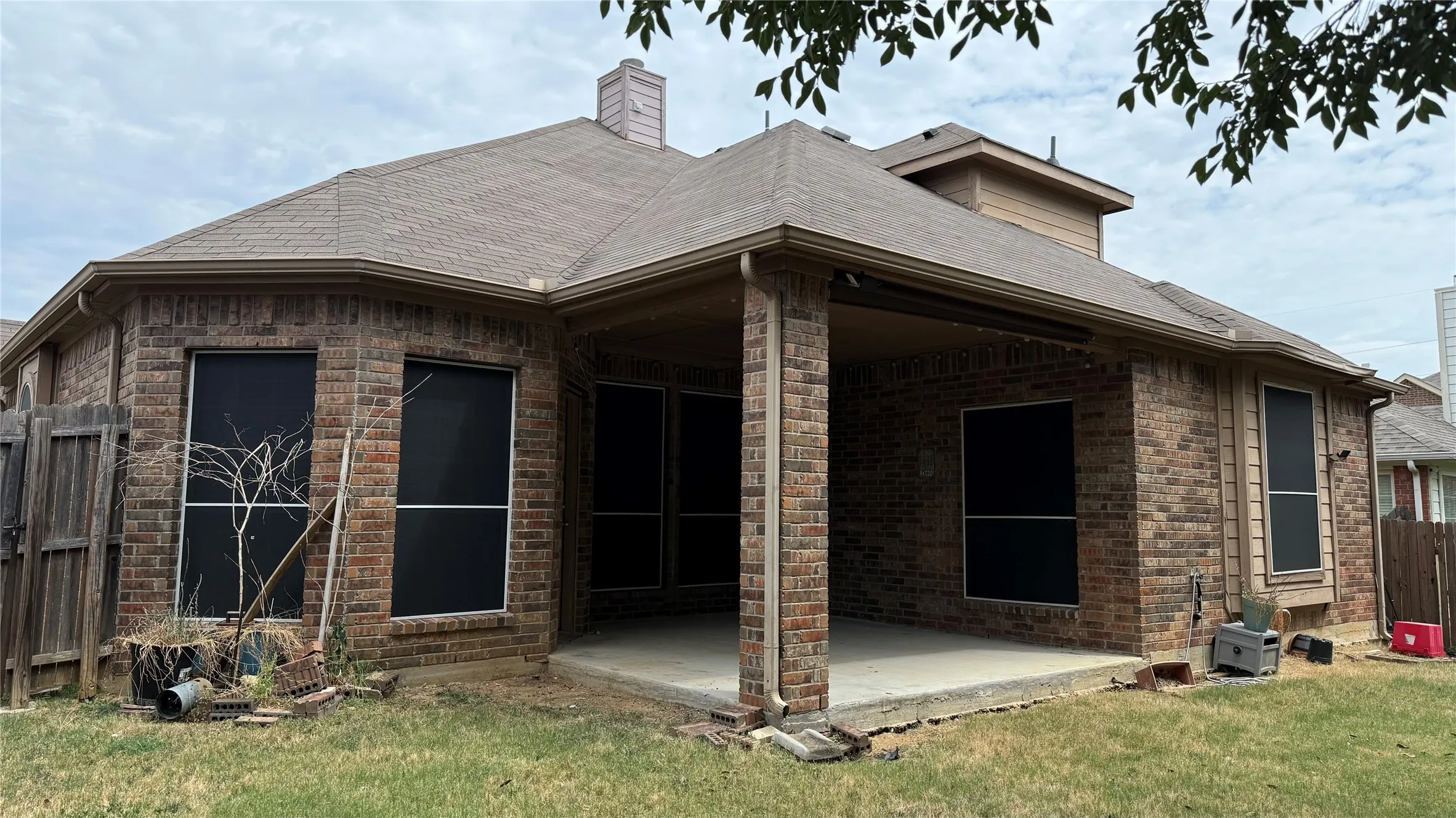 Brick exterior with a covered patio and a shingle roof