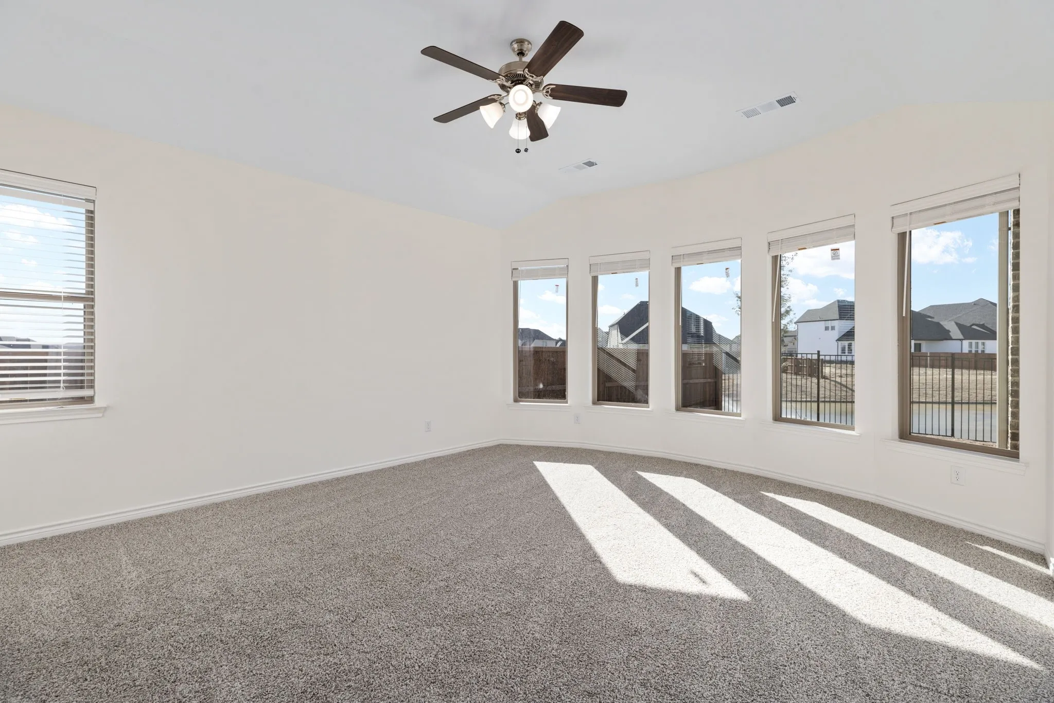 Designed for relaxation, the primary bedroom boasts plush carpet and a wall of windows overlooking the backyard.