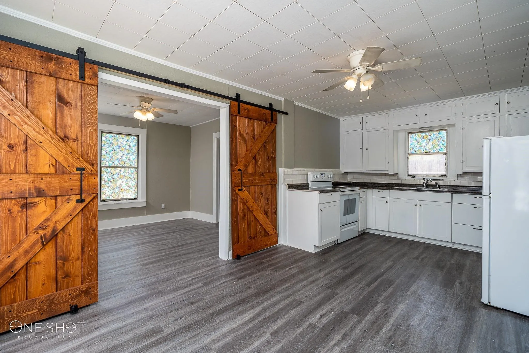 Kitchen featuring dark hardwood / wood-style flooring, white appliances, a barn door, and ceiling fan