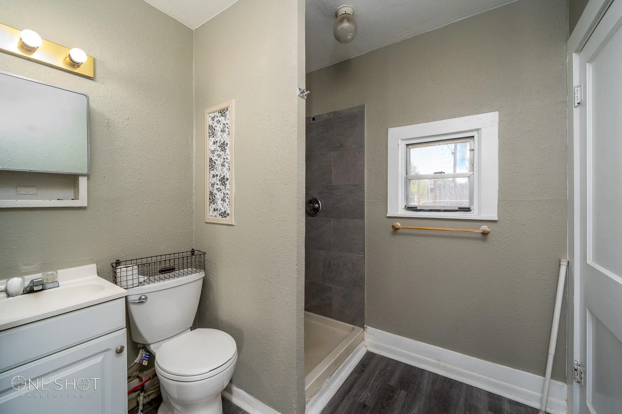 Bathroom with tiled shower, vanity, hardwood / wood-style floors, and toilet