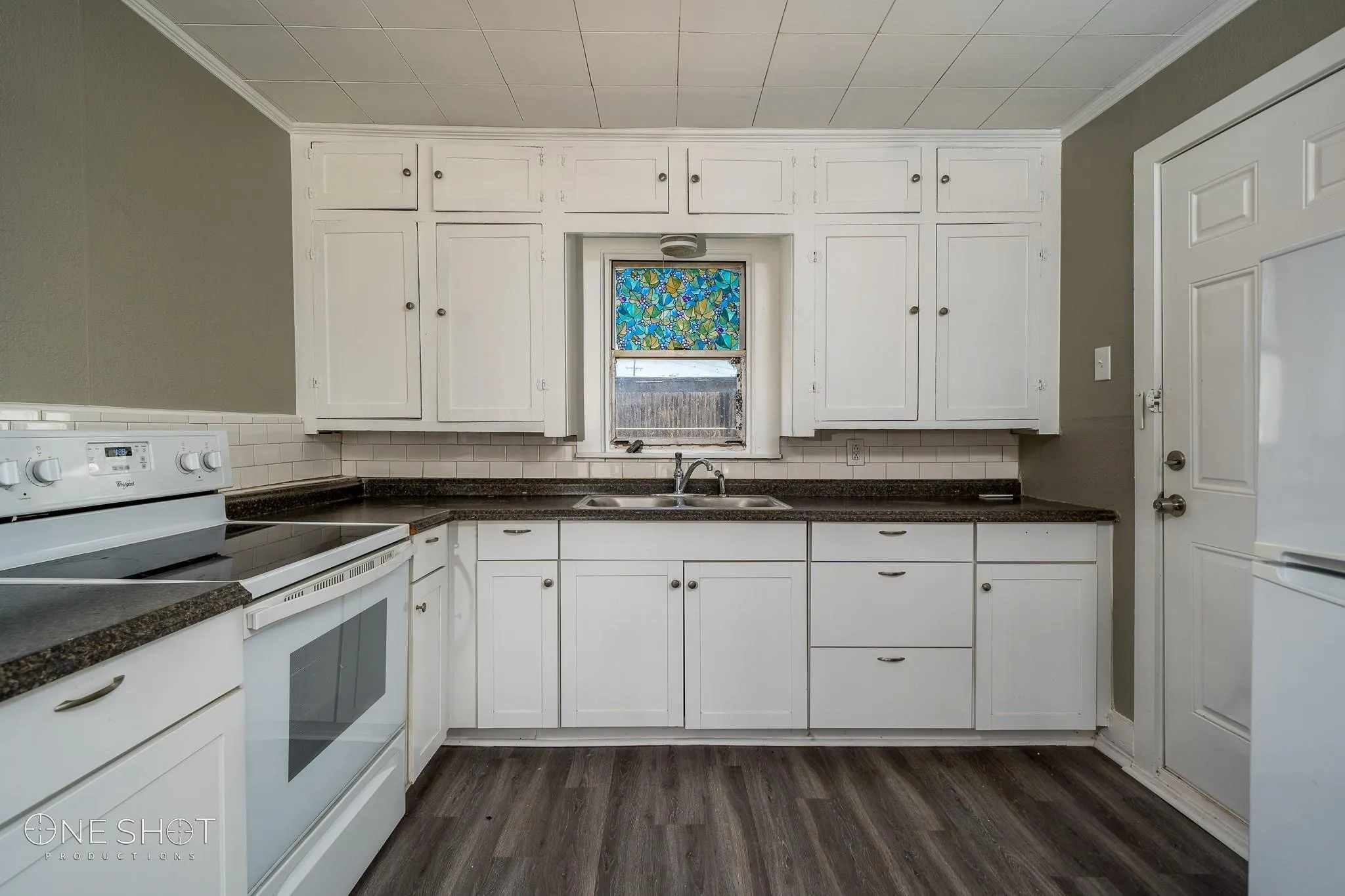 Kitchen with sink, white cabinetry, dark hardwood / wood-style floors, and white appliances