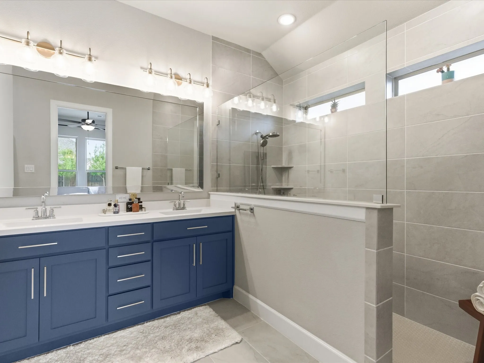 elegant bathroom featuring stylish blue cabinetry, dual sinks, and a sleek glass-enclosed shower, creating a sophisticated and functional space for everyday routines