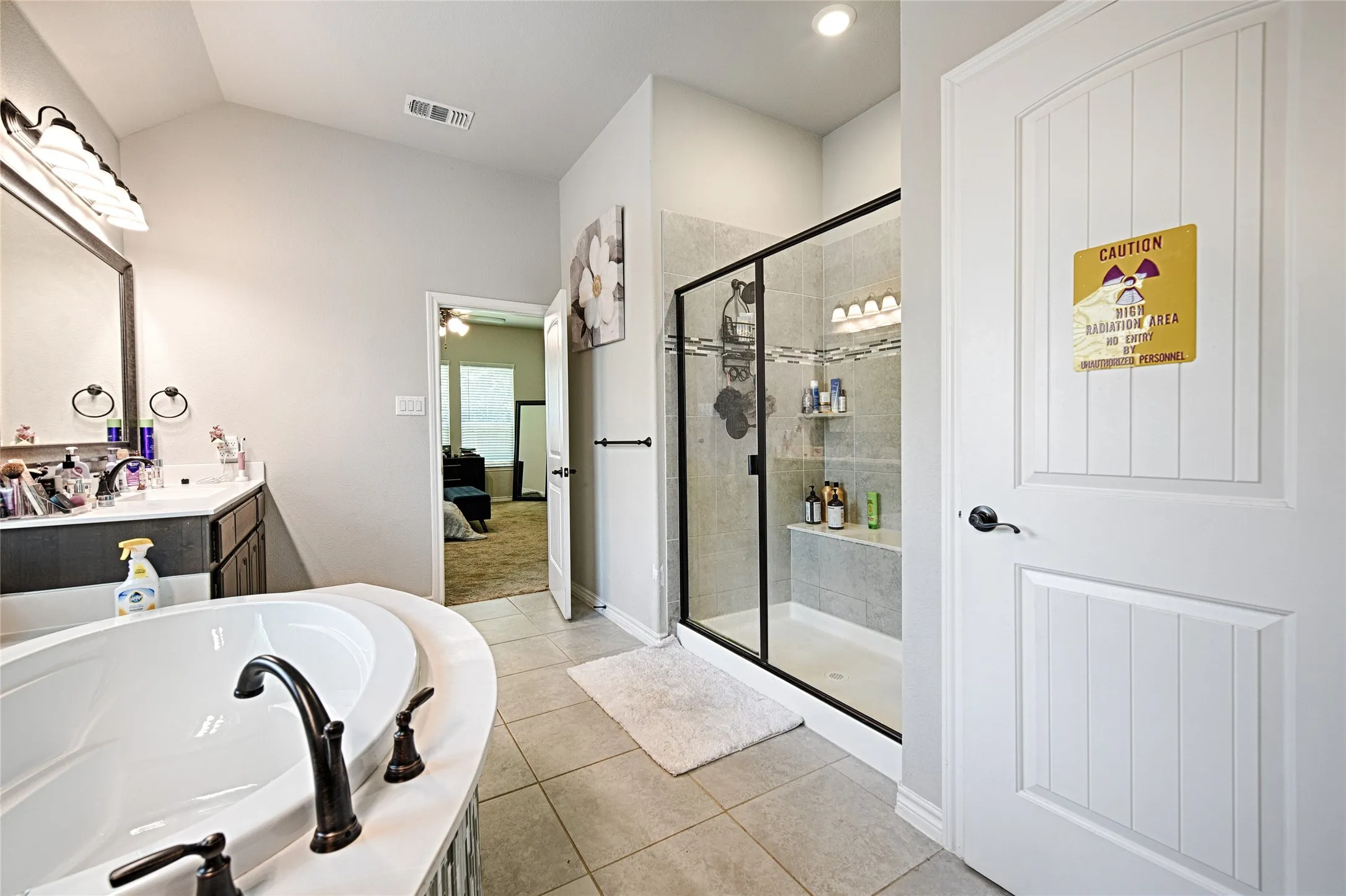 Bathroom featuring tile floors, vanity, shower with separate bathtub, and vaulted ceiling