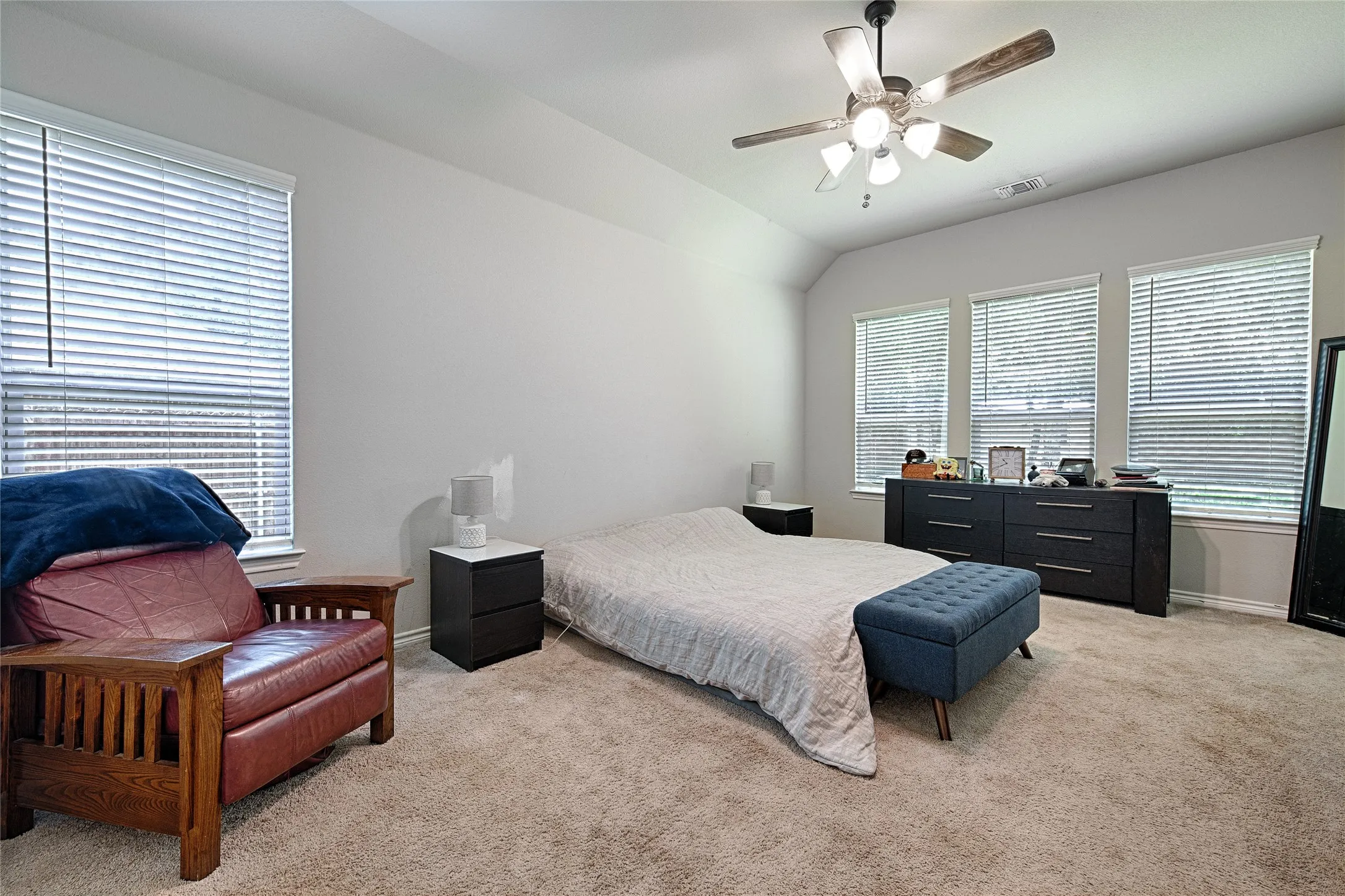 Carpeted bedroom with ceiling fan and multiple windows