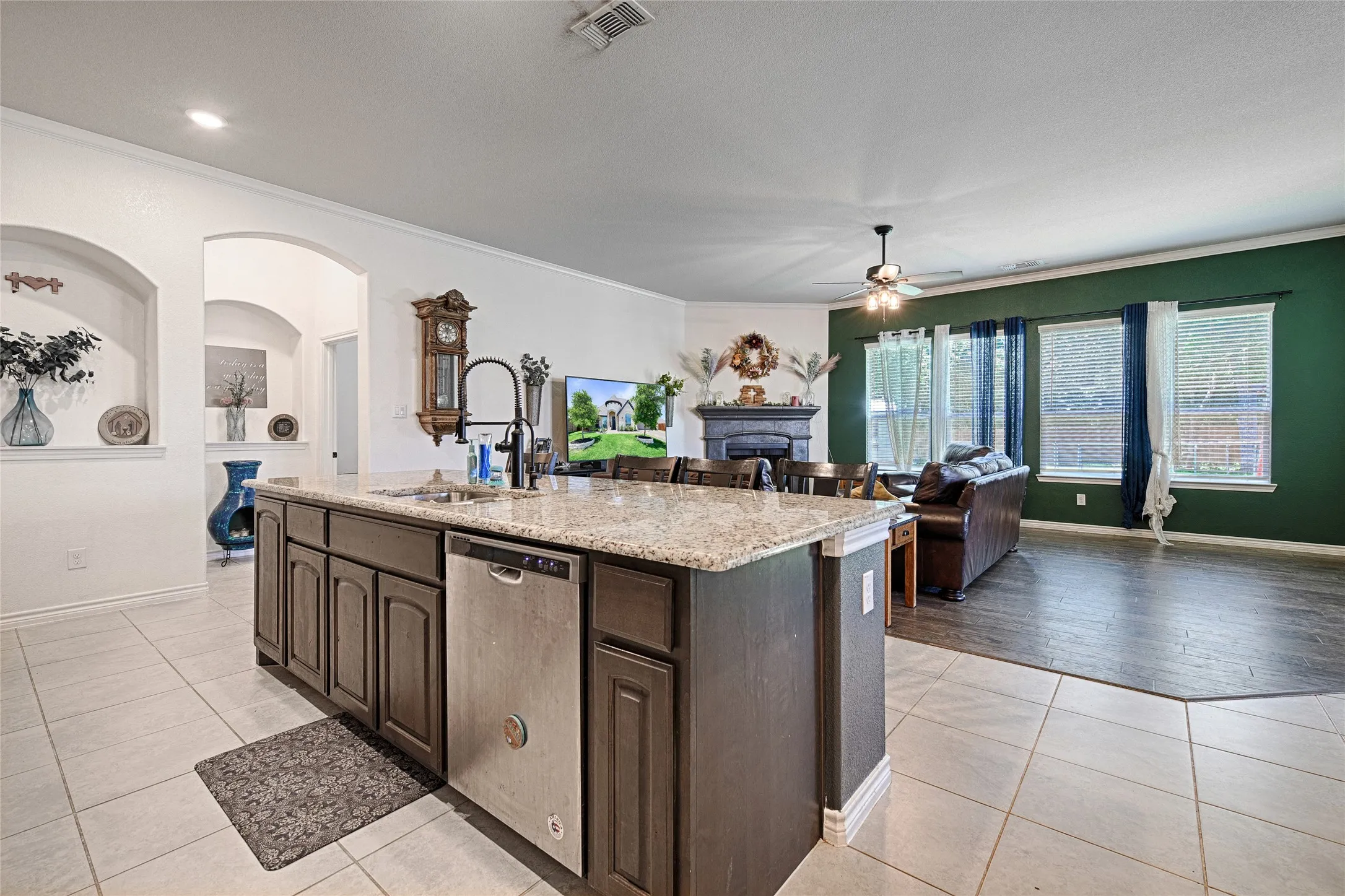 Kitchen featuring dishwasher, a center island with sink, ceiling fan, and dark brown cabinets