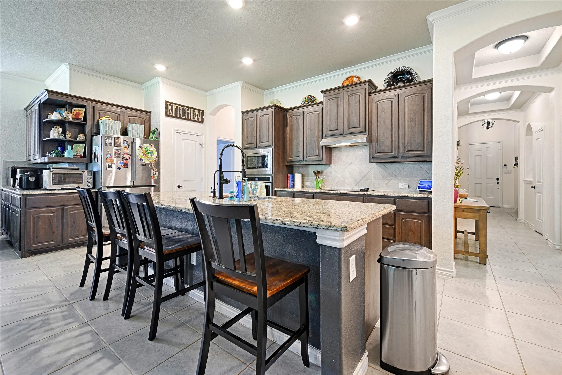 Kitchen featuring crown molding, a kitchen island with sink, backsplash, and stainless steel appliances