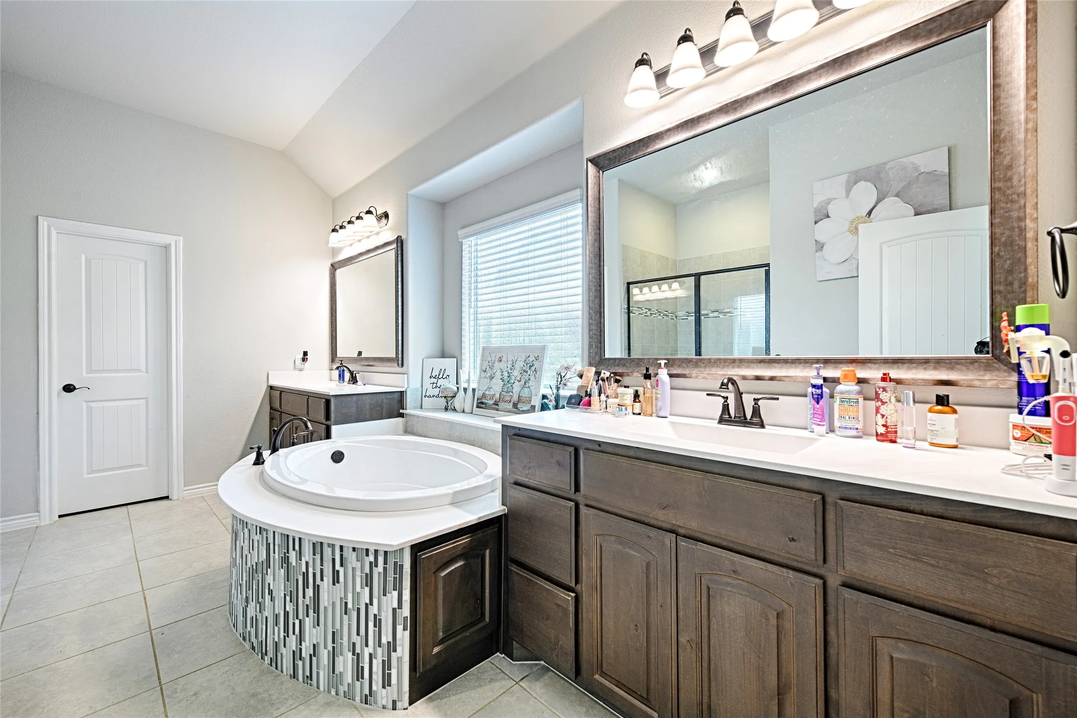 Bathroom featuring dual vanity, a bathtub, tile flooring, and lofted ceiling