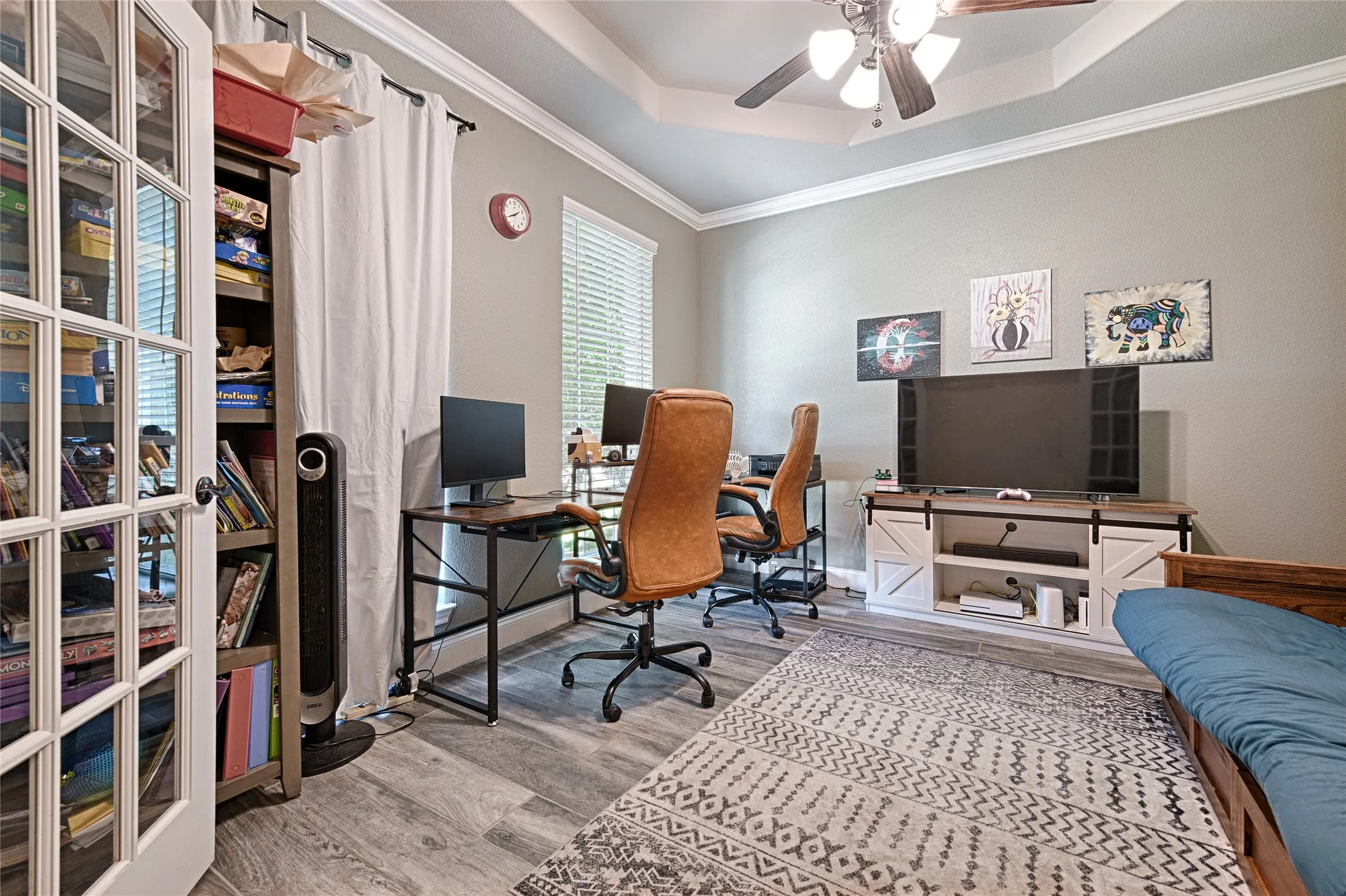 Office space featuring hardwood / wood-style floors, ornamental molding, ceiling fan, and a raised ceiling