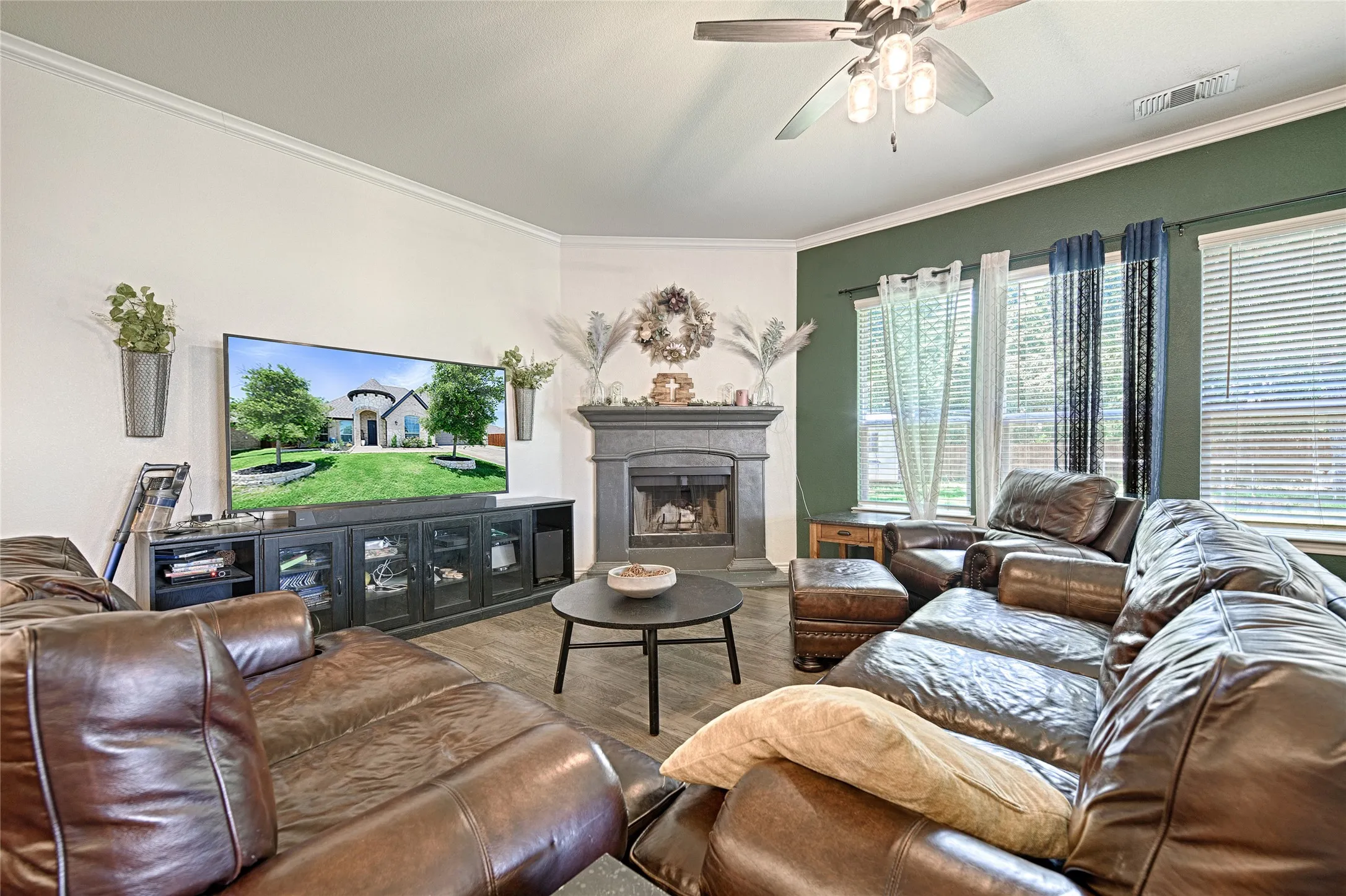 Living room with a premium fireplace, ornamental molding, wood-type flooring, and ceiling fan