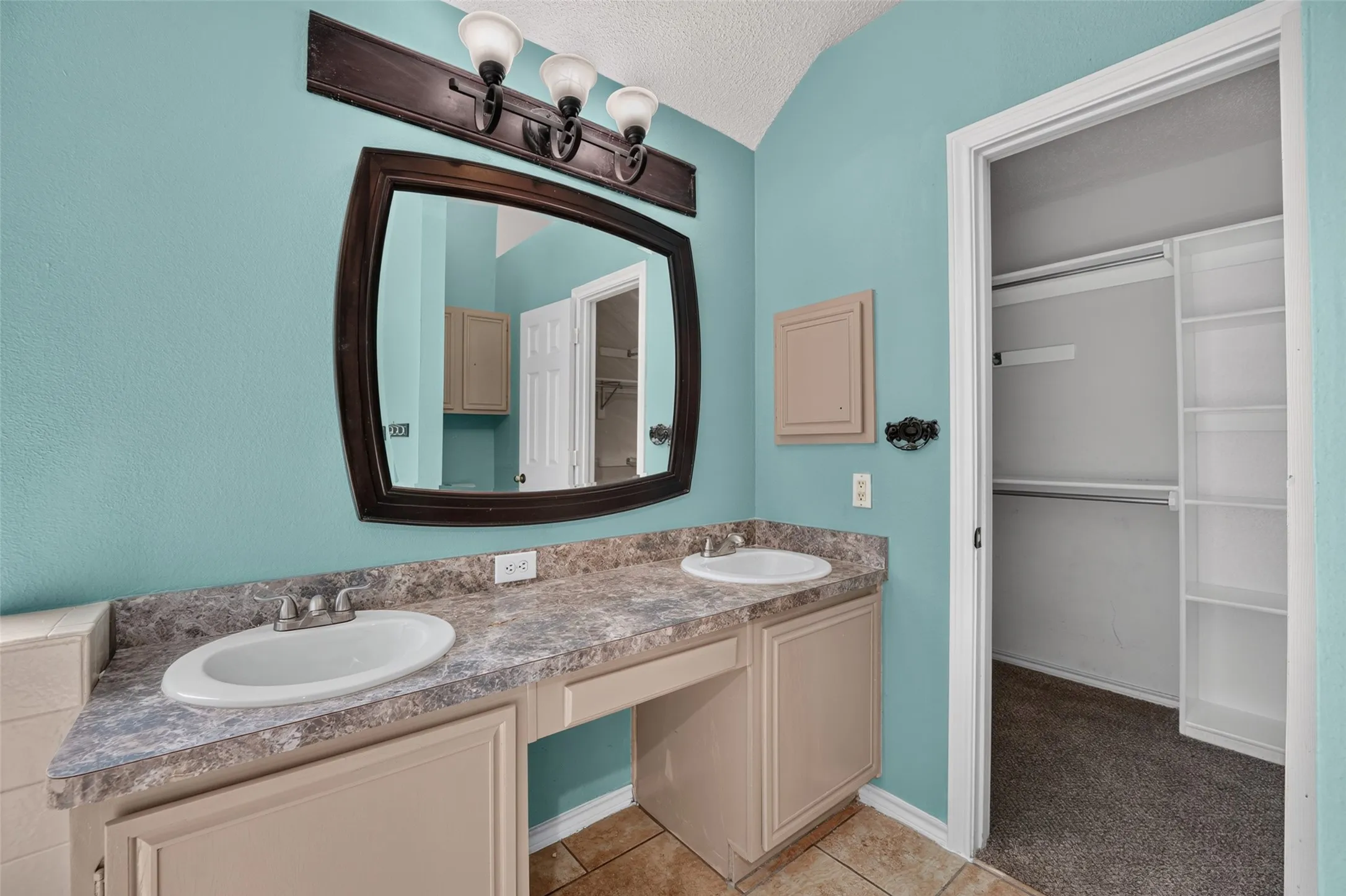 Double vanity with integrated sinks, wood-finish mirror, and built-in closet shelving