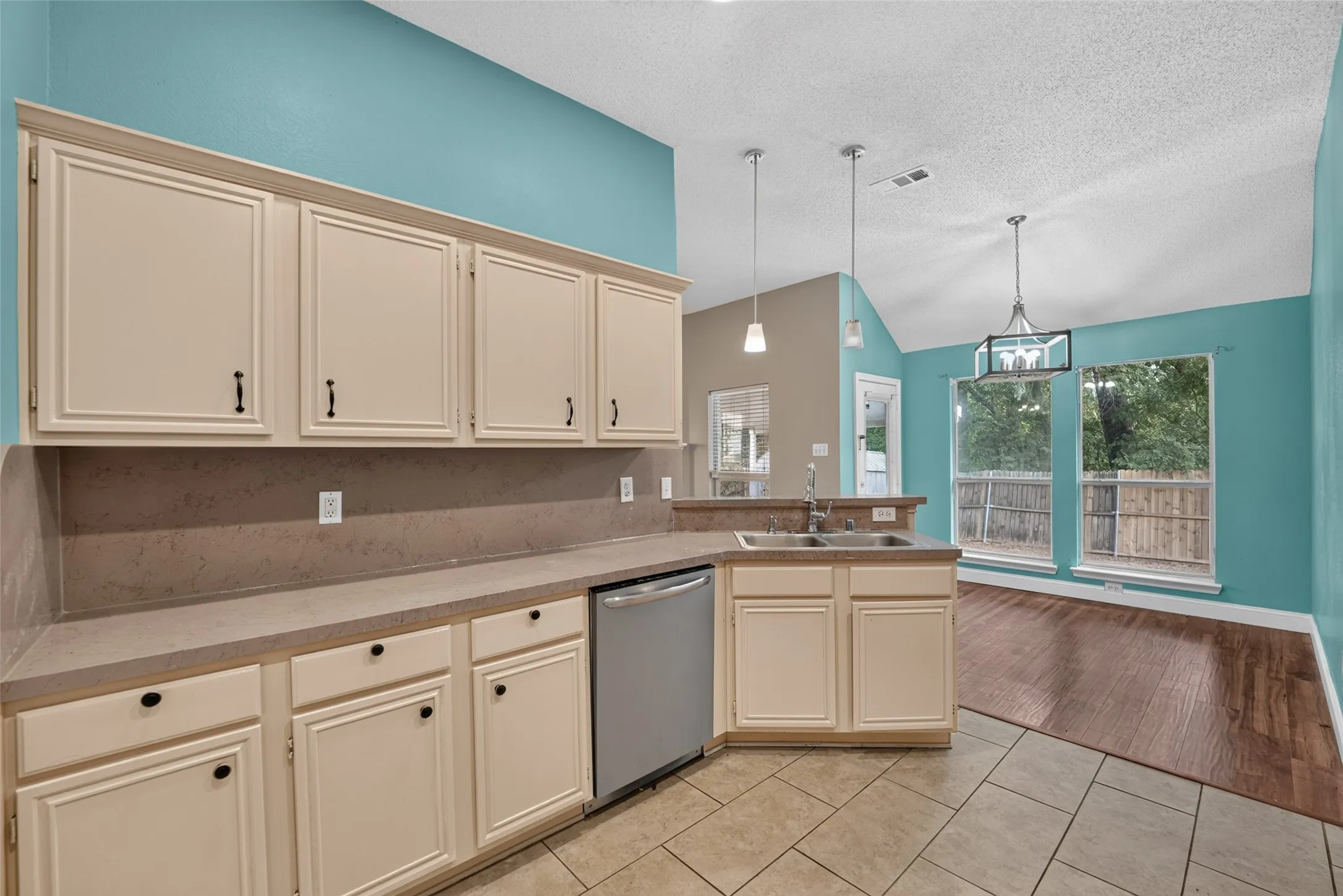Kitchen featuring cream-colored cabinetry, stainless steel dishwasher, tile flooring, and a double basin sink