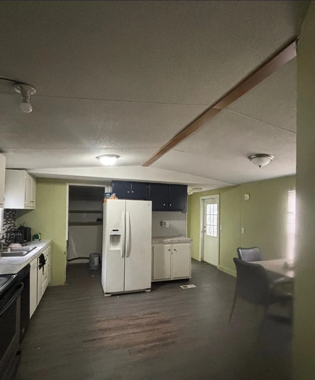 Kitchen area featuring wood-finish flooring, white cabinetry, dark contrasting upper cabinetry, and a white refrigerator
