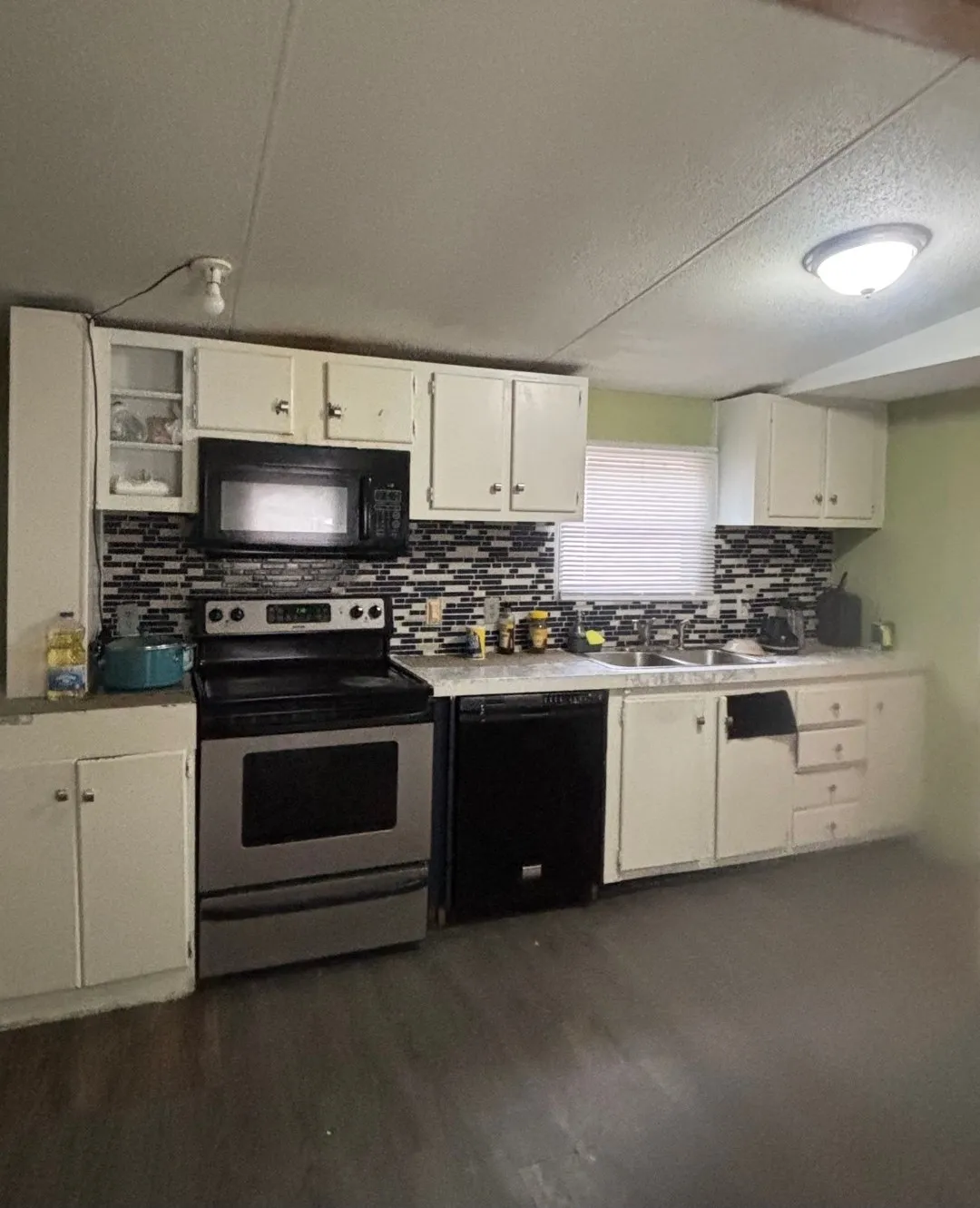 Kitchen featuring white cabinetry, a mosaic tile backsplash, a stainless steel range, and a black dishwasher