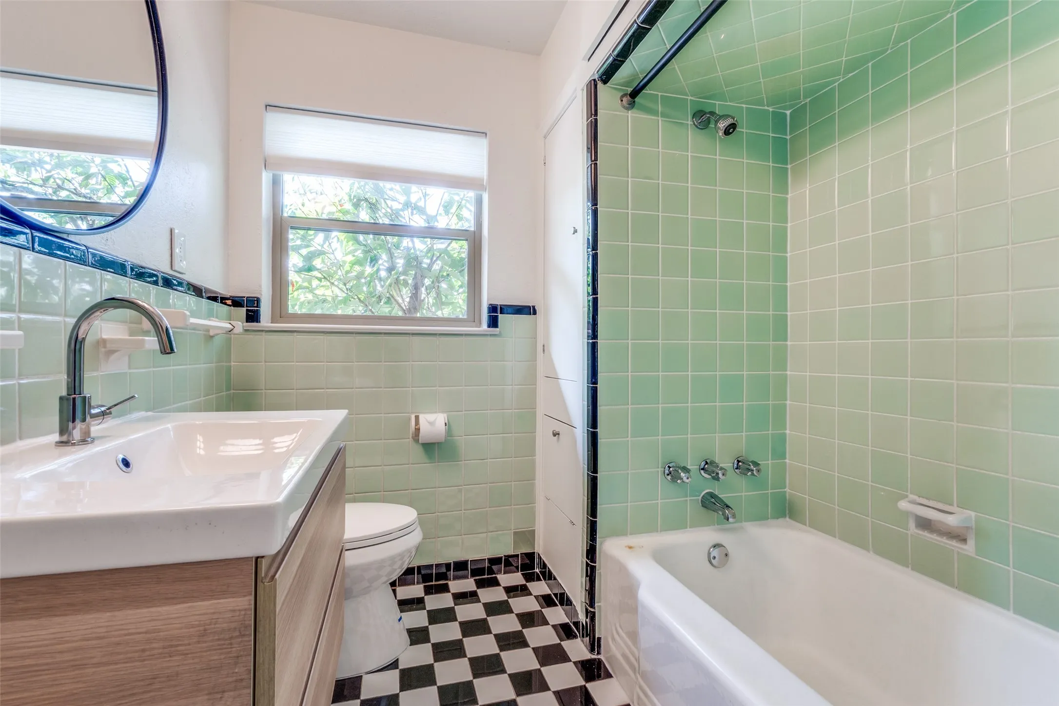 Full bath featuring vanity, tile walls, toilet, shower / washtub combination, and wainscoting