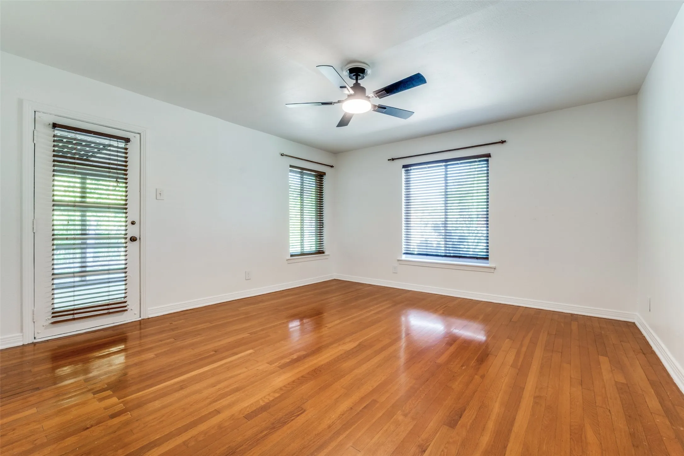 Empty room featuring baseboards, a ceiling fan, light wood-type flooring, and plenty of natural light