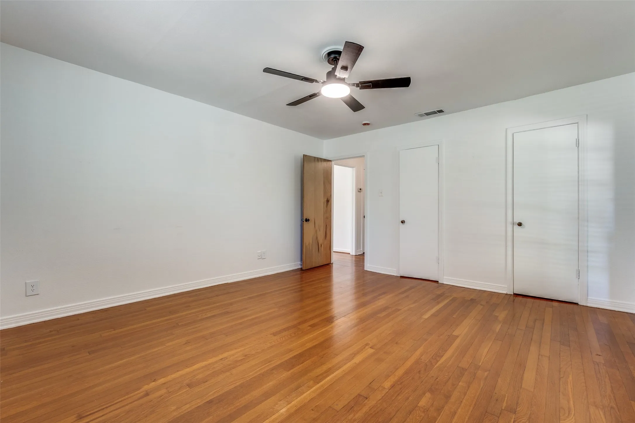 Unfurnished bedroom with baseboards, light wood-style flooring, visible vents, and a ceiling fan