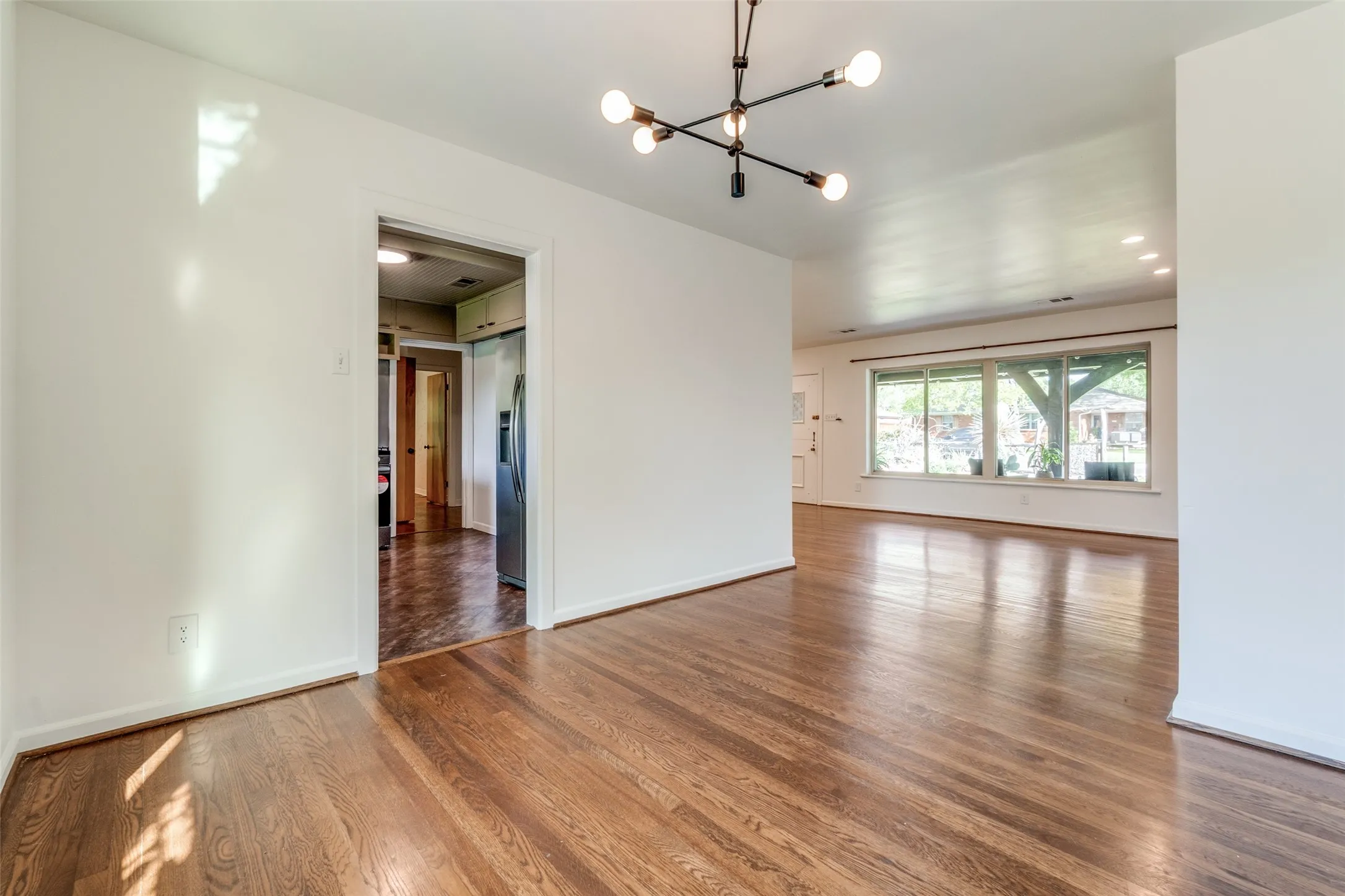 Empty room with baseboards, wood finished floors, and an inviting chandelier