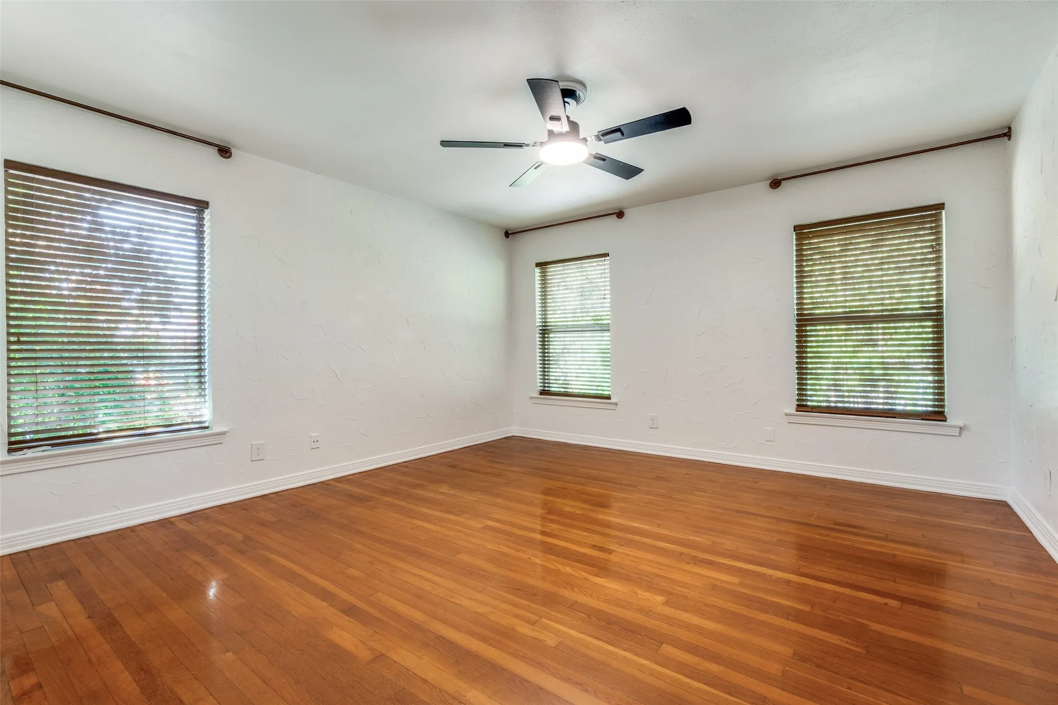 Spare room featuring hardwood / wood-style floors, baseboards, and a ceiling fan