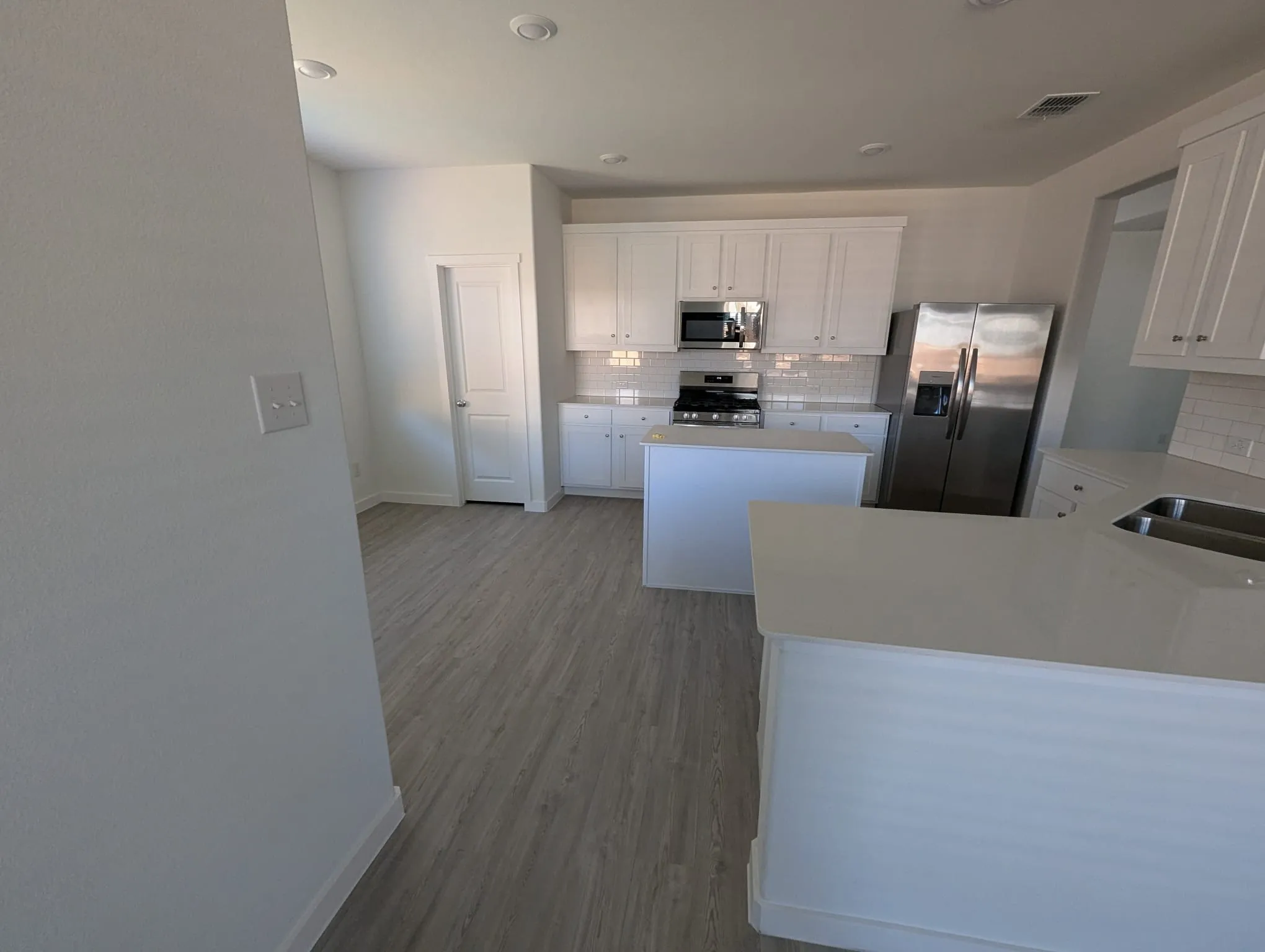 Kitchen featuring backsplash, hardwood / wood-style floors, white cabinets, and stainless steel appliances