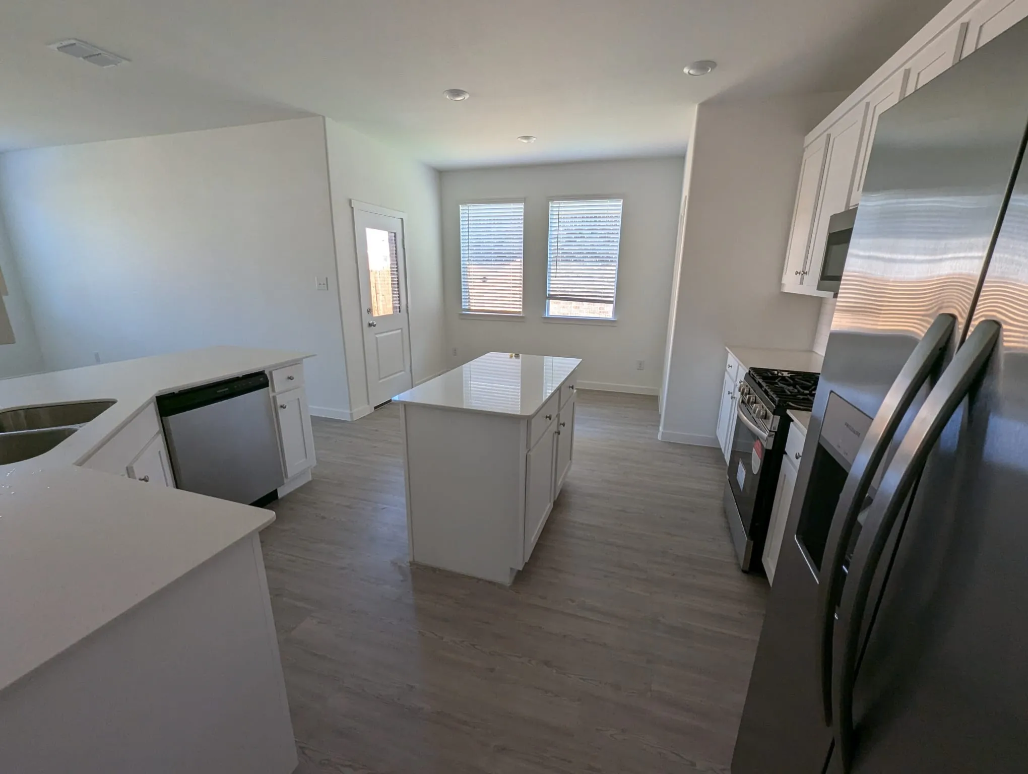 Kitchen with wood-type flooring, a center island, stainless steel appliances, and white cabinetry