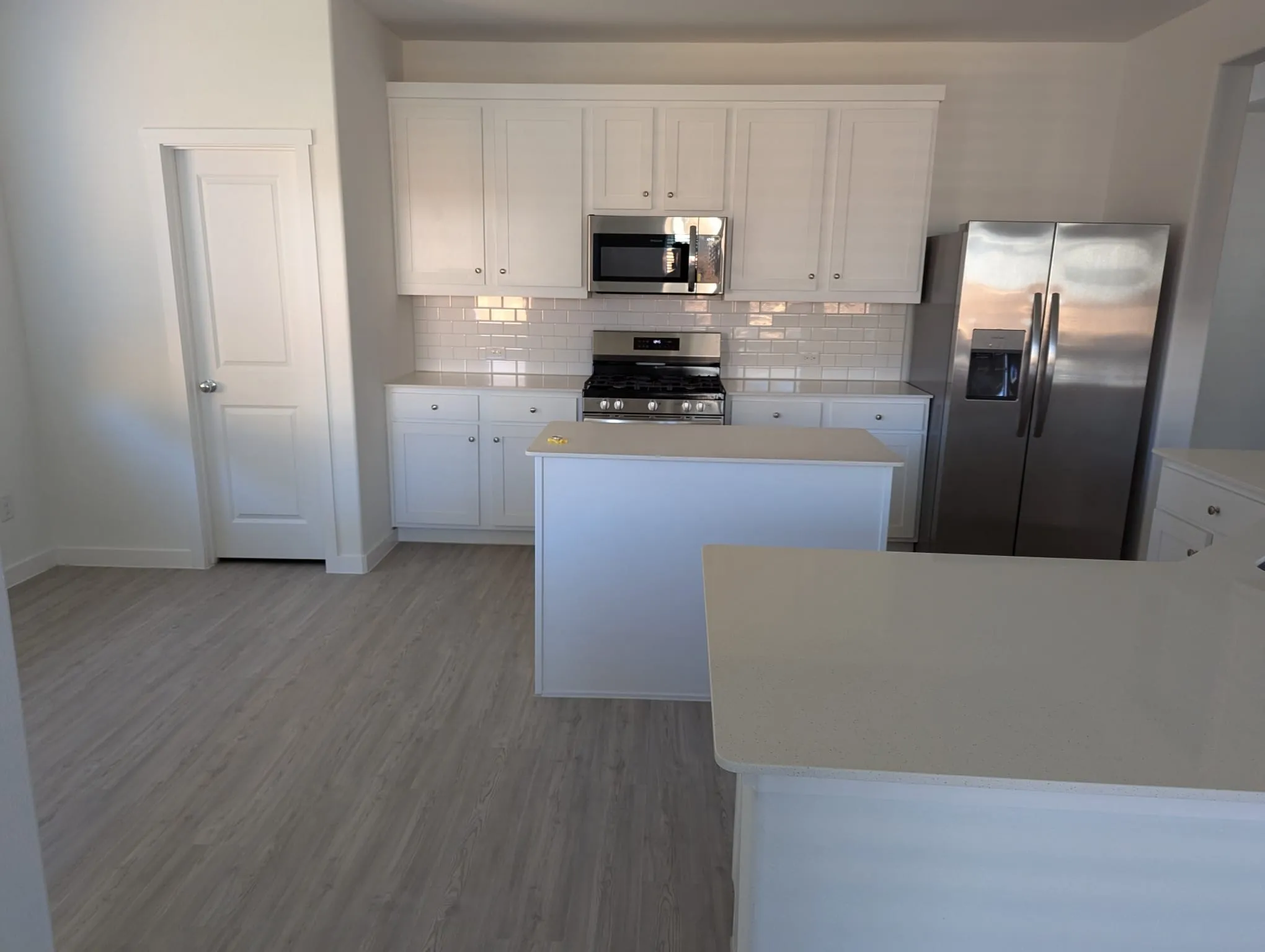 Kitchen featuring a center island, light hardwood / wood-style flooring, decorative backsplash, appliances with stainless steel finishes, and white cabinetry
