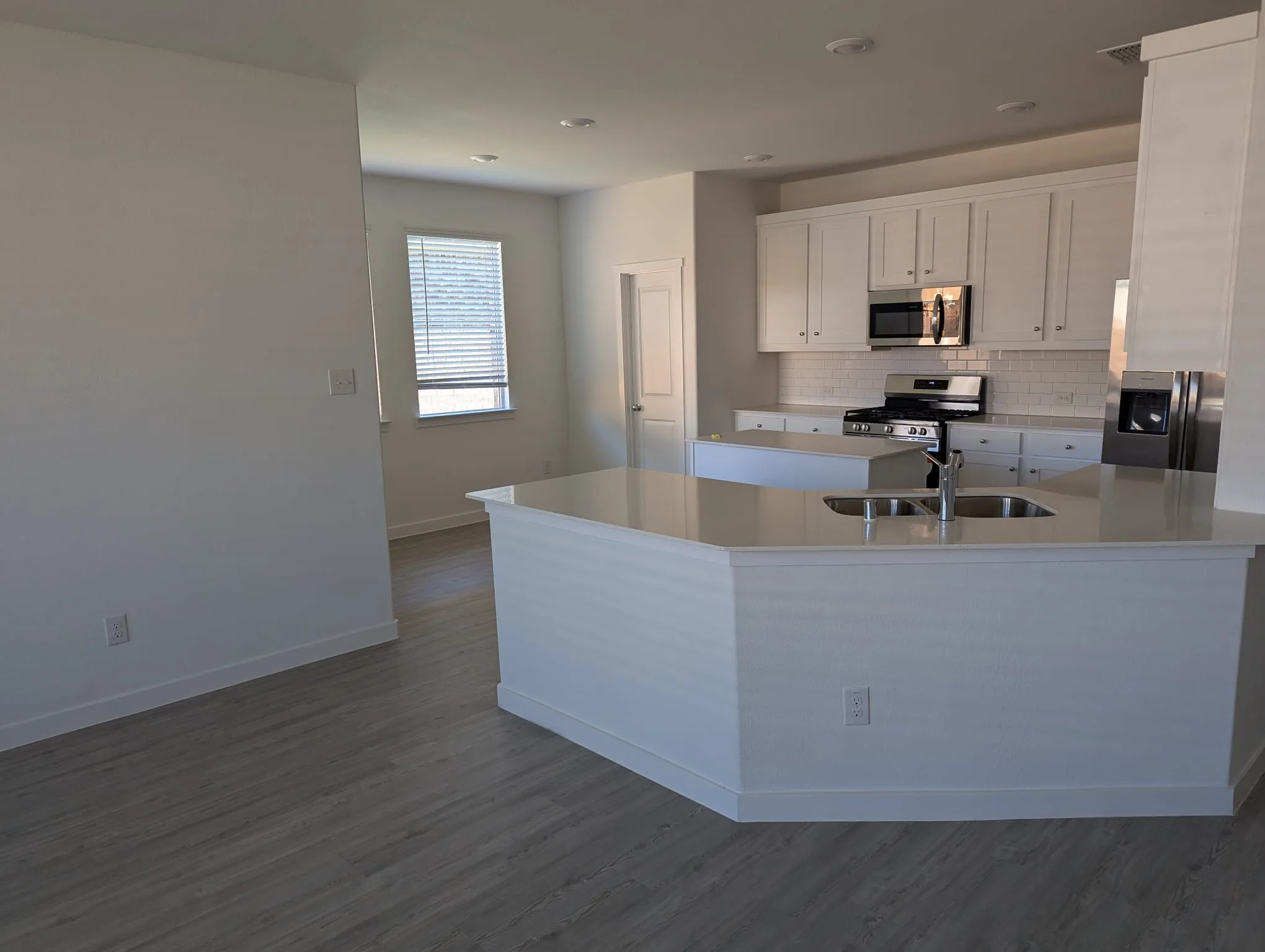Kitchen featuring sink, hardwood / wood-style flooring, decorative backsplash, appliances with stainless steel finishes, and white cabinetry